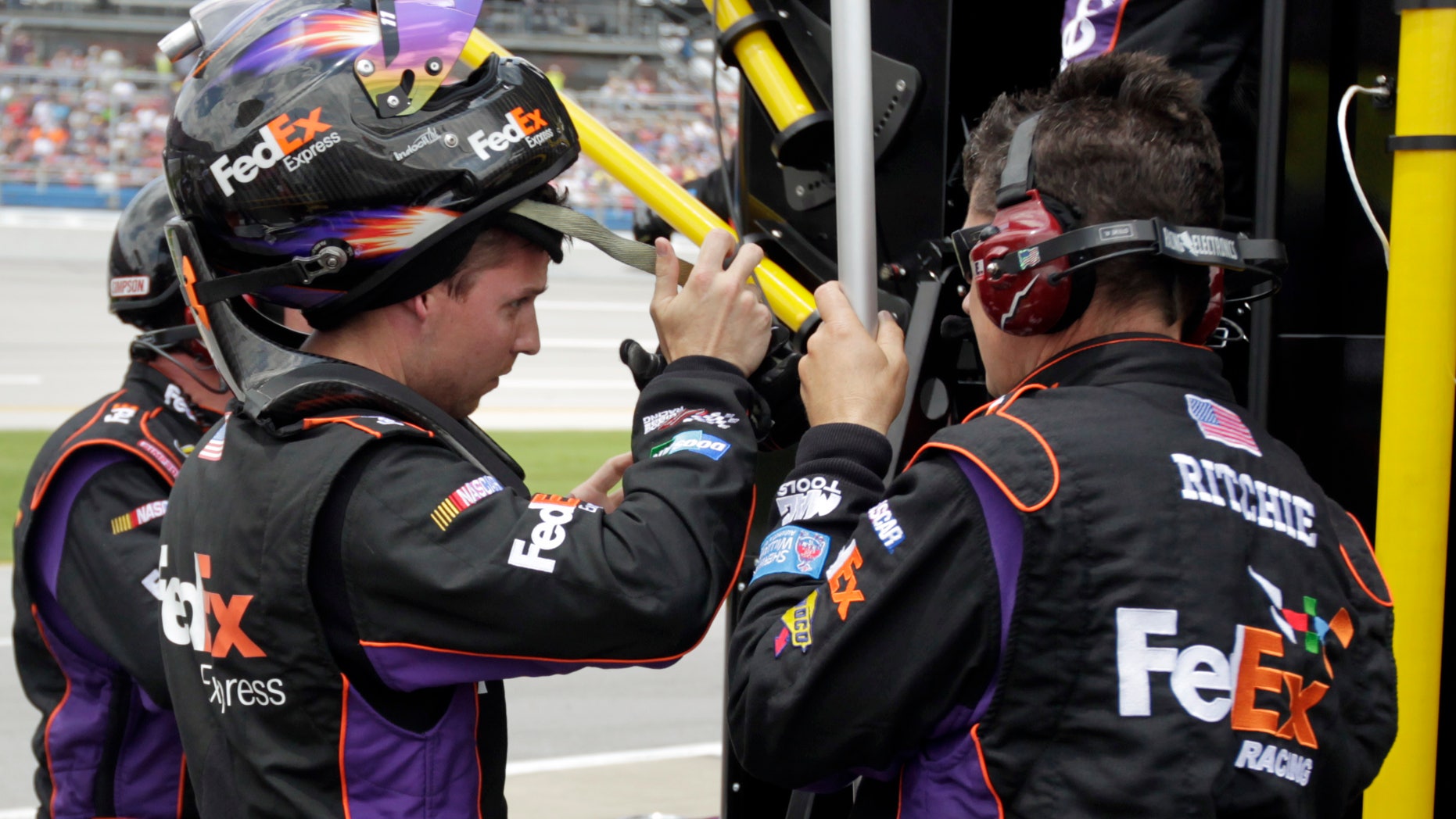 NASCAR Sprint Cup Series driver Denny Hamlin, left, talks with pit crew members after he was relieved by driver Brian Vickers on the first caution during the NASCAR Sprint Cup Series Aaron's 499 auto race at Talladega Superspeedway in Talladega, Ala., Sunday, May 5, 2013. (AP Photo/Jay Sailors)