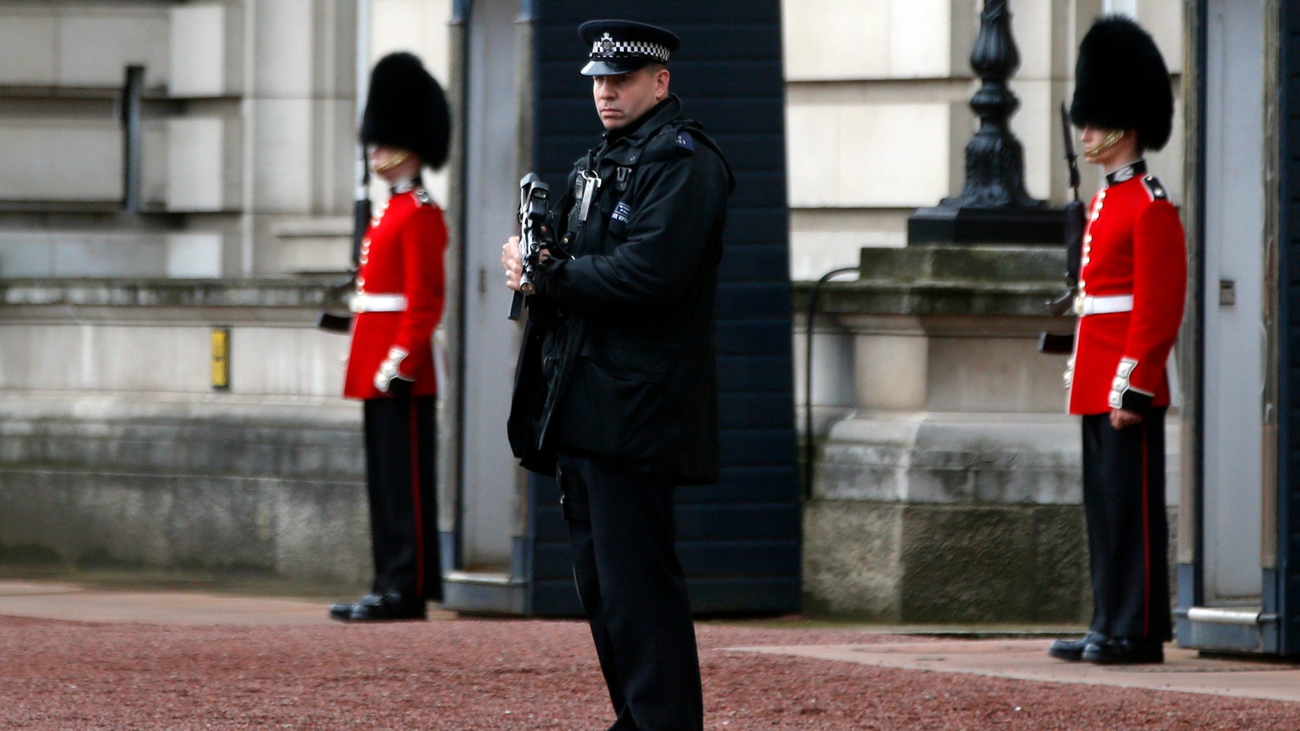 A British police officer guards the grounds of Buckingham Palace in central London, Monday, Oct. 14, 2013. British police arrested a man with a knife after he tried to dart through a gate at Buckingham Palace in London on Monday. The palace said Queen Elizabeth II was not in residence. Breaches of royal security are rare, but just a month ago police arrested two men over a suspected break-in at the palace. (AP Photo/Lefteris Pitarakis)