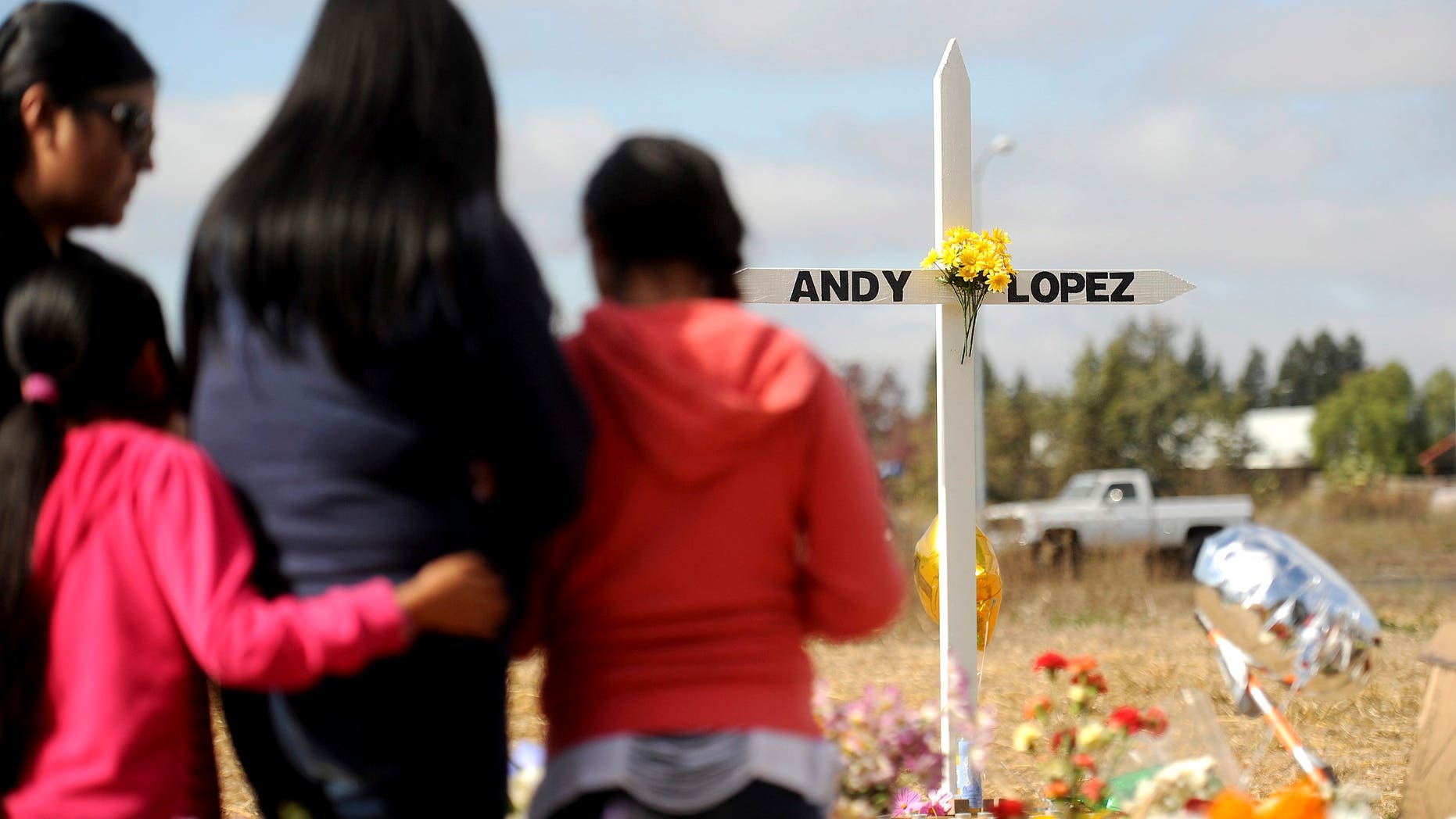 A family pauses at a memorial marking the location where sheriff's deputies shot and killed 13-year-old Andy Lopez in Santa Rosa, California, October 27, 2013.