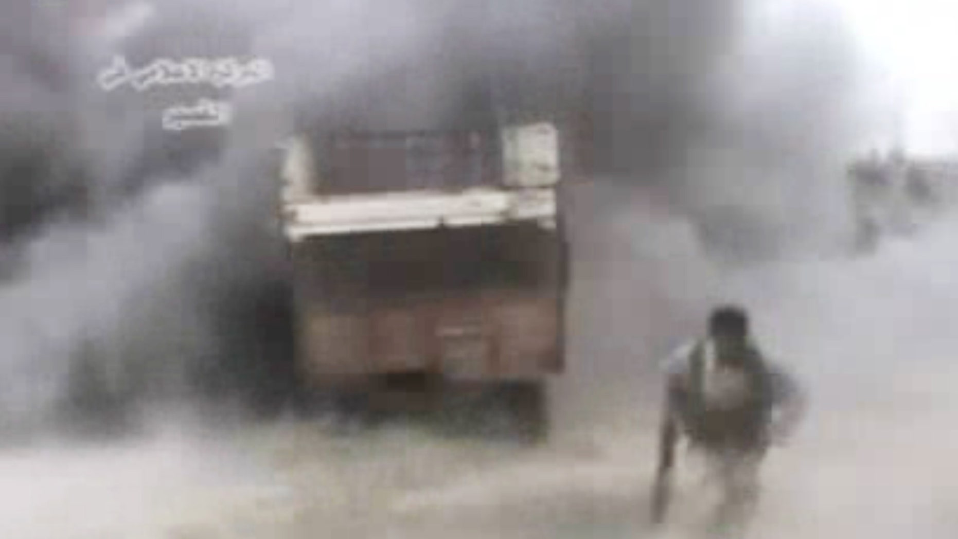 AP10ThingsToSee - In this image from amateur video obtained by a group called Ugarit News, a rebel runs from an explosion, Sunday, May 19, 2013 in Qusair, Syria. An intense battle drove rebels from large parts of Qusair, part of a withering government offensive aimed at securing a strategic land corridor from Damascus to the Mediterranean coast. (AP Photo)