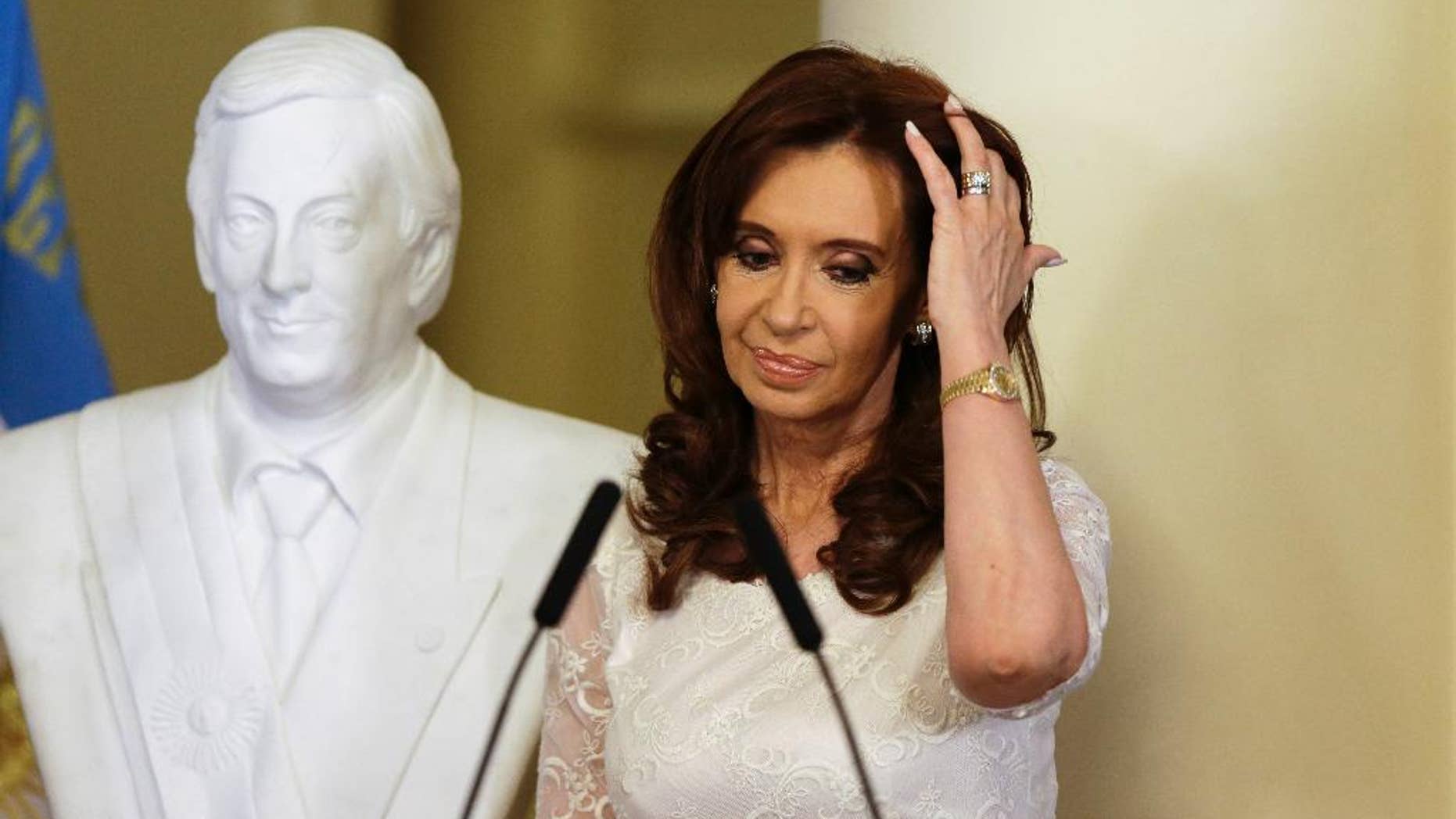 FILE - In this Dec. 9, 2015 file photo, Argentina's President Cristina Fernandez pushes her hair back after unveiling a bust of her late husband, and former president, Nestor Kirchner, at the presidential palace in Buenos Aires, Argentina. A judge in Argentina has ordered Fernandez to face trial in a case where she is accused of defrauding the state as part of her government's handling of the dollar futures market. (AP Photo/Ricardo Mazalan, File)