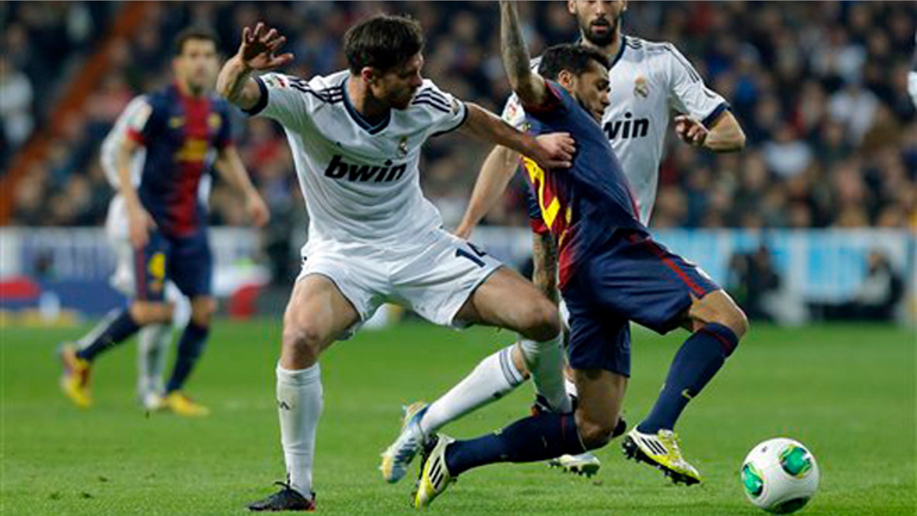 El jugador brasileño del Barcelona, Dani Alves, centro, disputa un balón en un partido contra Real Madrid por las semifinales de la Copa del Rey el miércoles, 30 de enero de 2013, en Madrid. (AP Photo/Andres Kudacki)