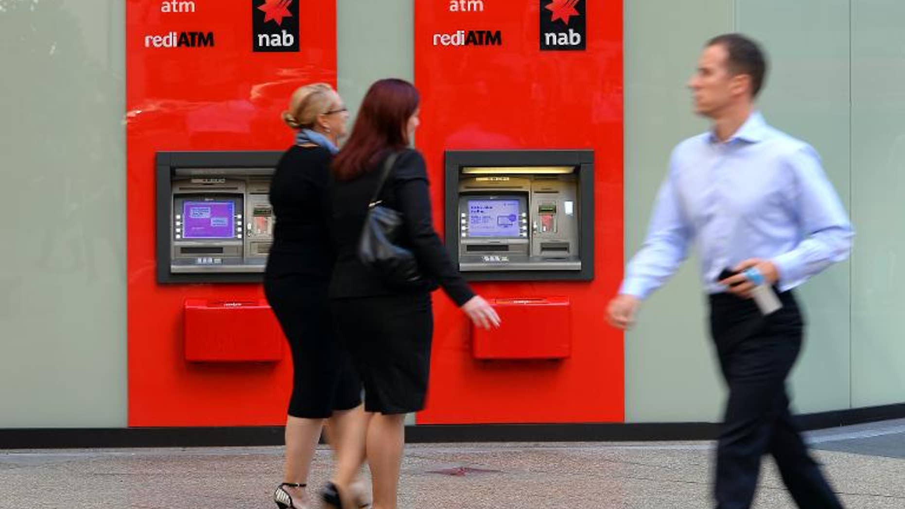 People walk past National Australia Bank (NAB) automated teller machines in the central business district of Sydney on May 9, 2013. British regulators Thursday said they had fined NAB-owned Clydesdale Bank almost ??9.0 million.