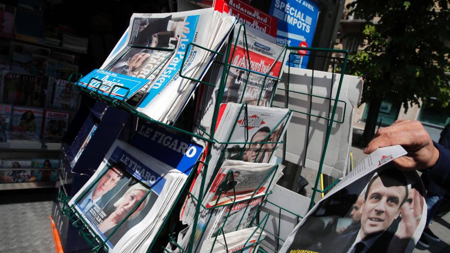 A man takes a French national newspaper reporting on the winners of the first round of the French presidential election, centrist candidate Emmanuel Macron and far-right candidate Marine Le Pen, on a newsstand in Paris, France, Monday, April 24, 2017. French voters shut out the country's political mainstream from the presidency for the first time in the country's modern history, and on Monday found themselves being courted across the spectrum for the runoff election. (AP Photo/Christophe Ena)