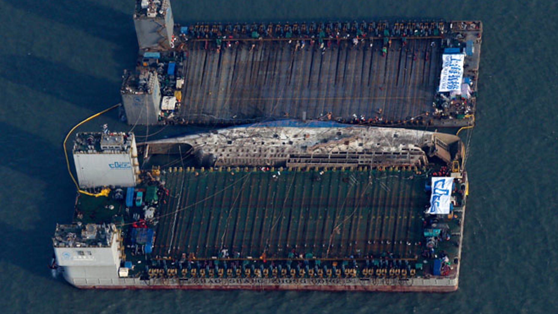 MARCH 23: Workers try to raise the sunken Sewol ferry, center, between two barges during the salvage operation in waters off Jindo, South Korea