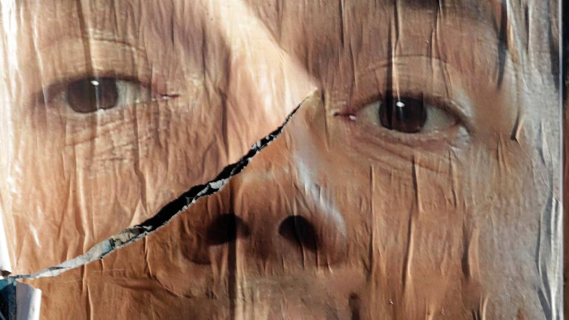A torn anti-referendum poster shows Premier Matteo Renzi, in Rome, Monday, Dec. 5, 2016. Italian voters dealt Premier Renzi a resounding rebuke early Monday by rejecting his proposed constitutional reforms, plunging Europe's fourth-largest economy into political and economic uncertainty. (AP Photo/Gregorio Borgia)