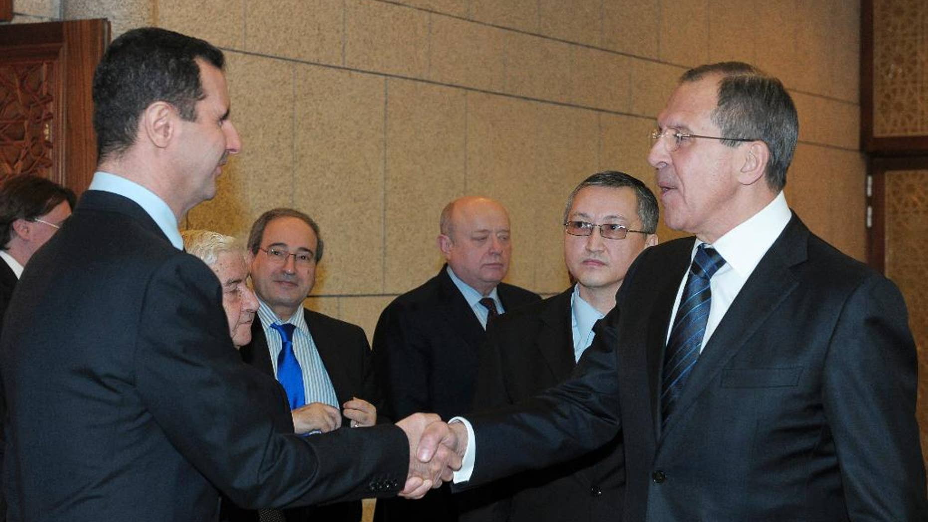 FILE - In this Feb. 7, 2012 file photo, Syrian President Bashar Assad, left, shakes hands with Russian Foreign Minister Sergey Lavrov after talks in Damascus, Syria. Lavrov said Thursday, Sept. 10, 2015, that Russian aircraft flying into Syria have been delivering weapons along with humanitarian supplies. (AP Photo/Pool, File)