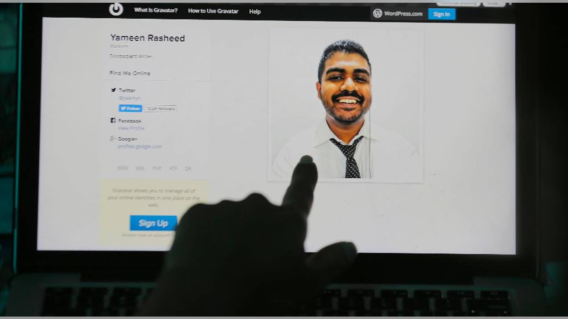 A Sri Lankan woman points to a portrait of Maldivian blogger Yameen Rasheed on his blog "The Daily Panic" in Colombo, Sri Lanka, Sunday, April 23, 2017. Police in the Maldives said in a statement that Rasheed was found Sunday morning with multiple stab wounds in a house in the capital, Male. He died at a hospital. (AP Photo/Eranga Jayawardena)