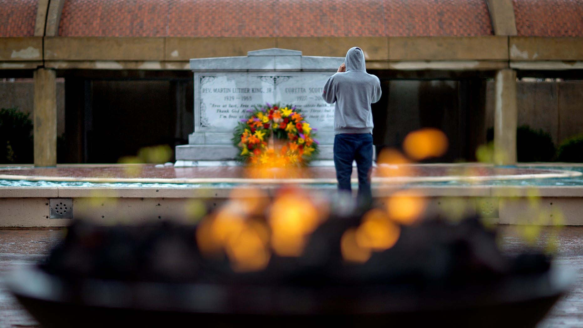 A visitor stands in front of the grave of Martin Luther King, Jr., as an eternal flame burns in the foreground on the 45th anniversary of the assassination of the civil rights leader, Thursday, April 4, 2013, in Atlanta. (AP Photo/David Goldman)