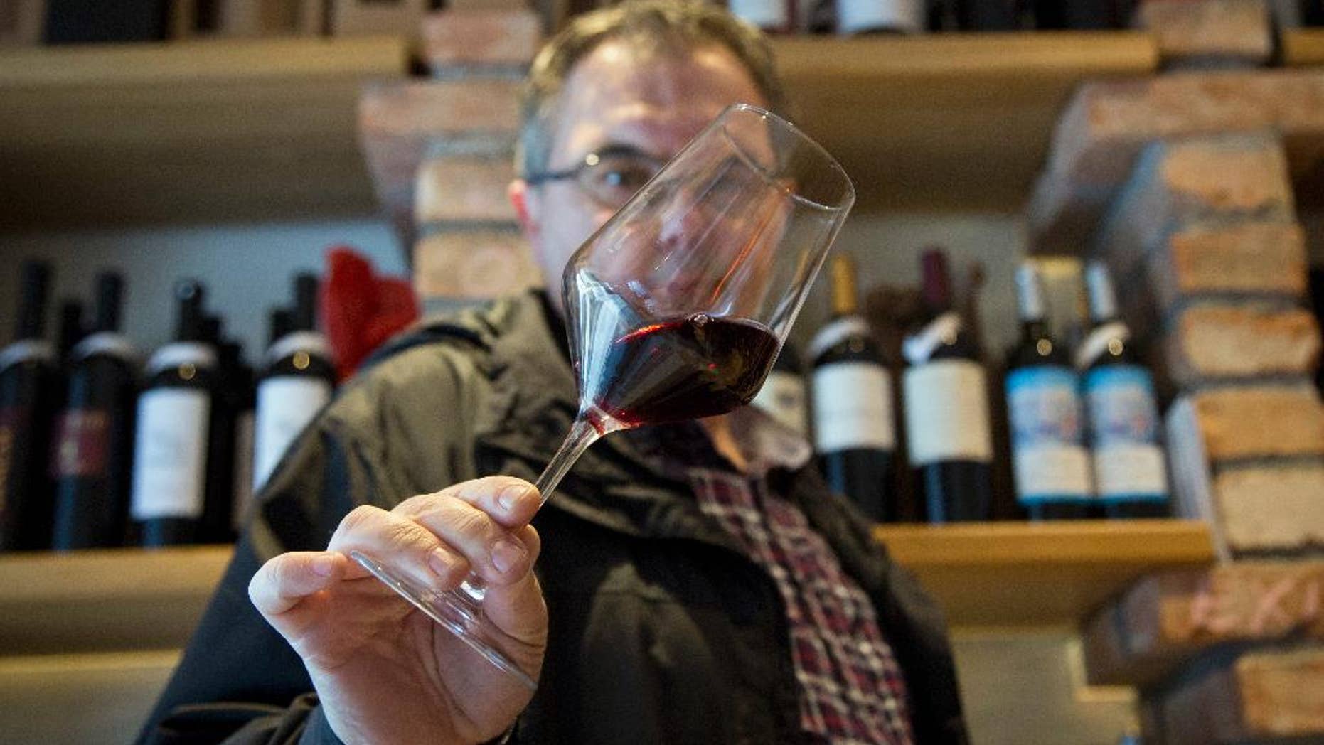 FILE - In this Wednesday, March 1, 2017 file photo, Robert Samek, a sommelier, inspects a glass of red wine at his wine shop in Zagreb, Croatia. Slovenian winemakers say they expect the European Commission to suspend the procedure of issuing a permit to Croatia to use the Teran red wine brand in the 28-nation bloc. The head of a Slovenian group to protect Teran, Marjan Colja, told The Associated Press on Friday, March 10 that his group has “no doubt” documentation presented by Croatia has been “partly forged.” (AP Photo/Darko Bandic, file)