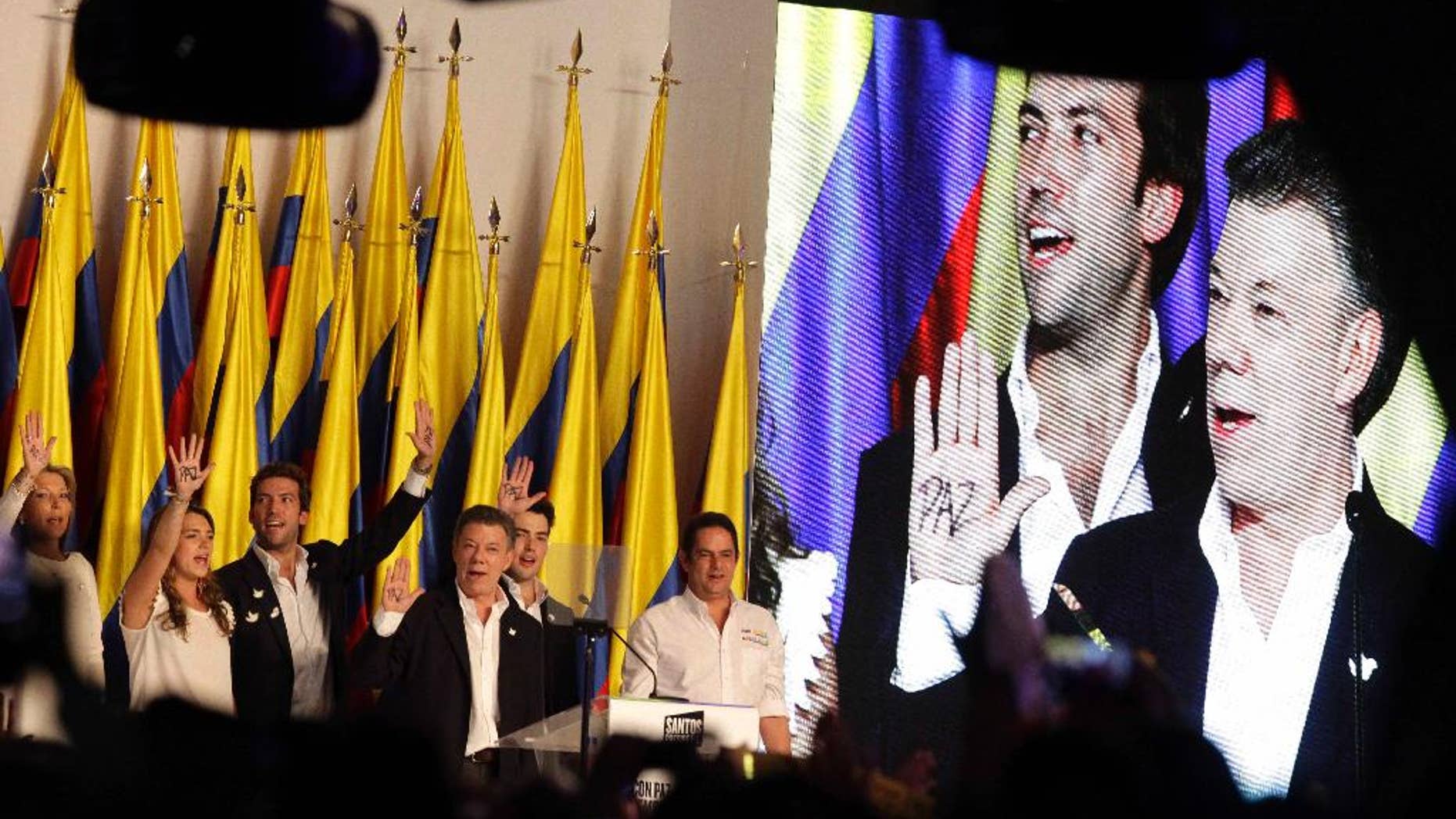 President Juan Manuel Santos, on screen at far right, celebrates winning the presidential runoff election, surrounded by his family at his campaign headquarters in Bogota, Colombia, Sunday, June 15, 2014. Behind Santos on the screen is his son Martin Santos. Santos defeated challenger Oscar Ivan Zuluaga, of the Democratic Center, and won a second four-year term. (AP Photo/Javier Galeano)