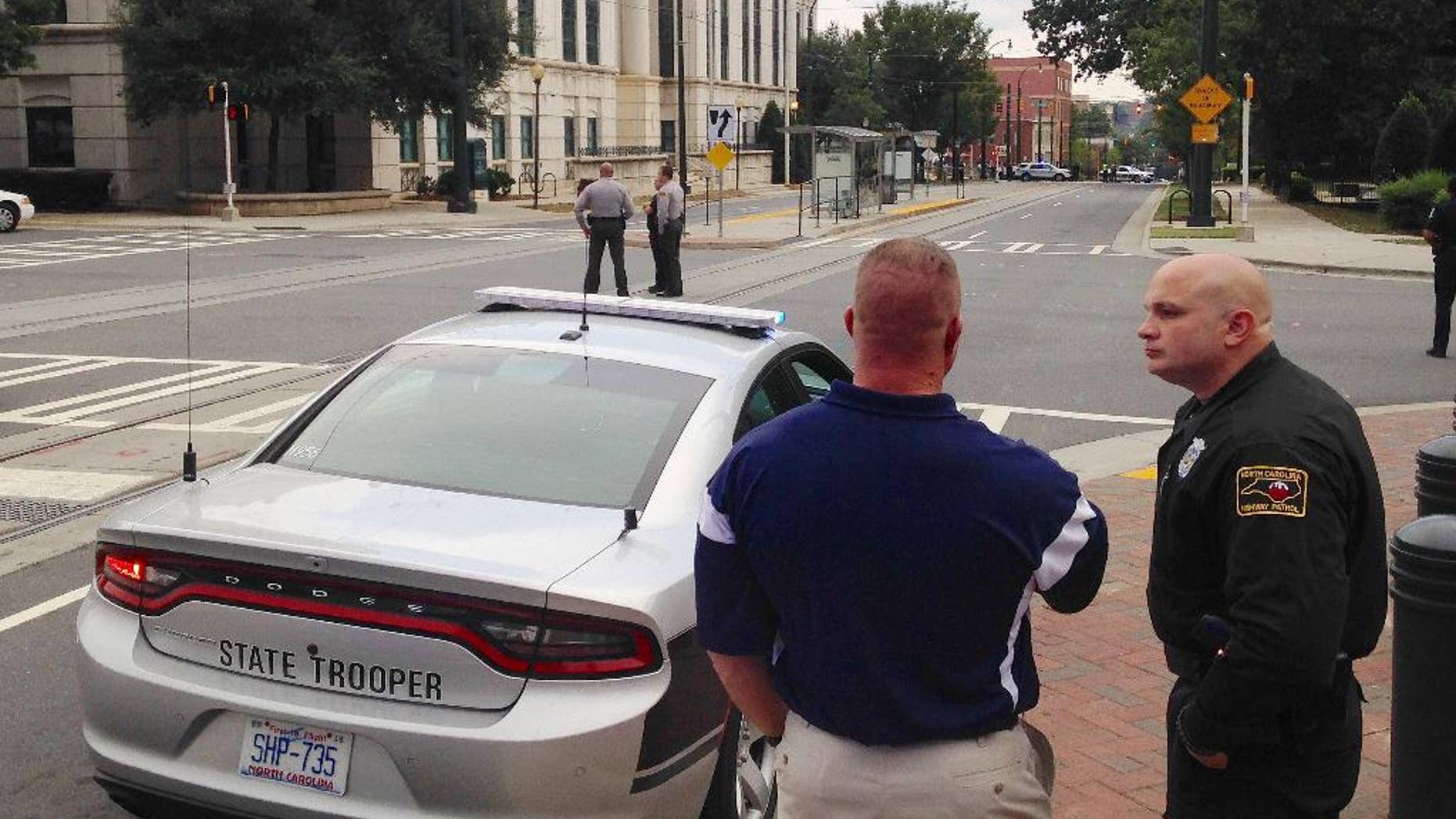 Law enforcement officers gather outside police headquarters in Charlotte, N.C., on Tuesday, Sept. 27, 2016, after a suspicious package was found inside the building. A city spokesman says the structure was evacuated and searched as a precaution following days of protests over the fatal police shooting of a black man. (AP Photo/Jay Reeves)