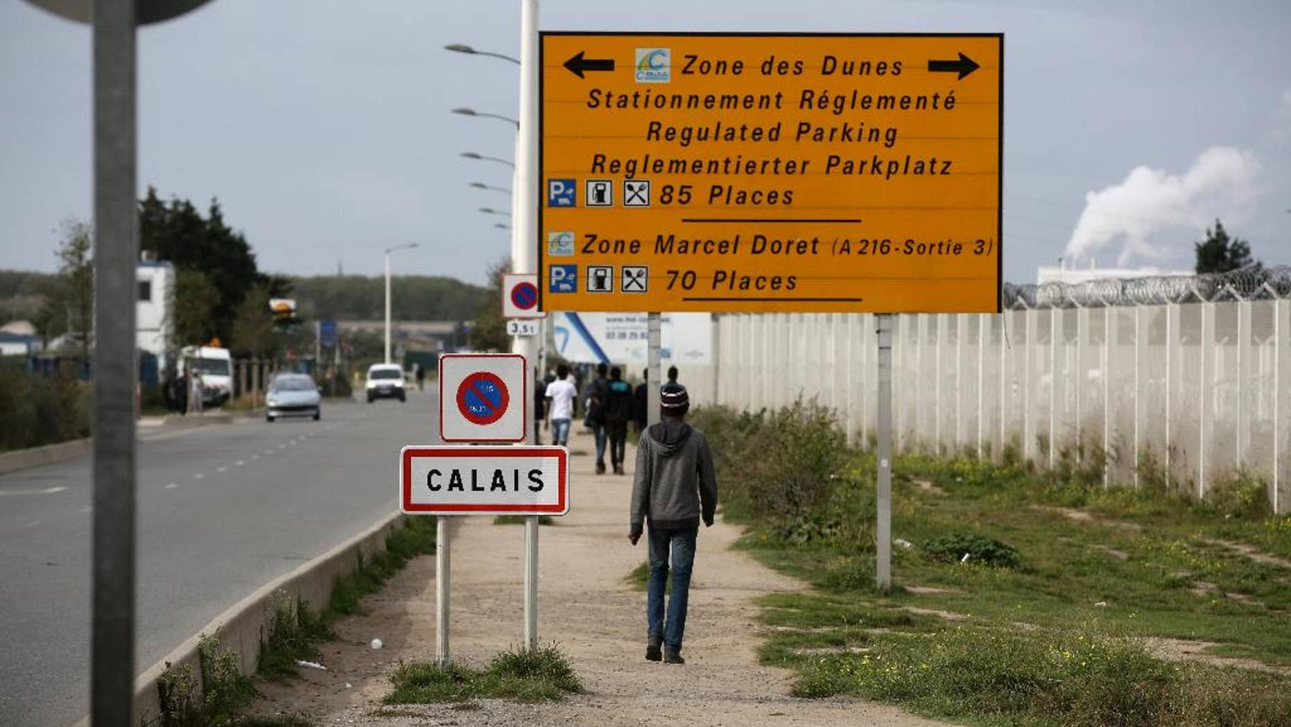 FILE - In this Monday, Sept. 26, 2016 file photo, a migrant walks outside the makeshift camp in Calais, northern France. French authorities have arrested and convicted a top smuggler and his accomplice who had reigned over desperate migrants trying to sneak to Britain. (AP Photo/Thibault Camus, File)