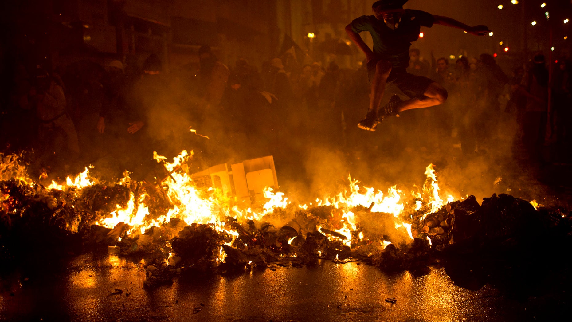 AP10ThingsToSee - A demonstrator jumps over a burning barricade at the Cinelandia Square during a march in support of teachers on strike in Rio de Janeiro on Monday, Oct. 7, 2013. Teachers have been on strike demanding better pay for nearly two months. (AP Photo/Felipe Dana, File)