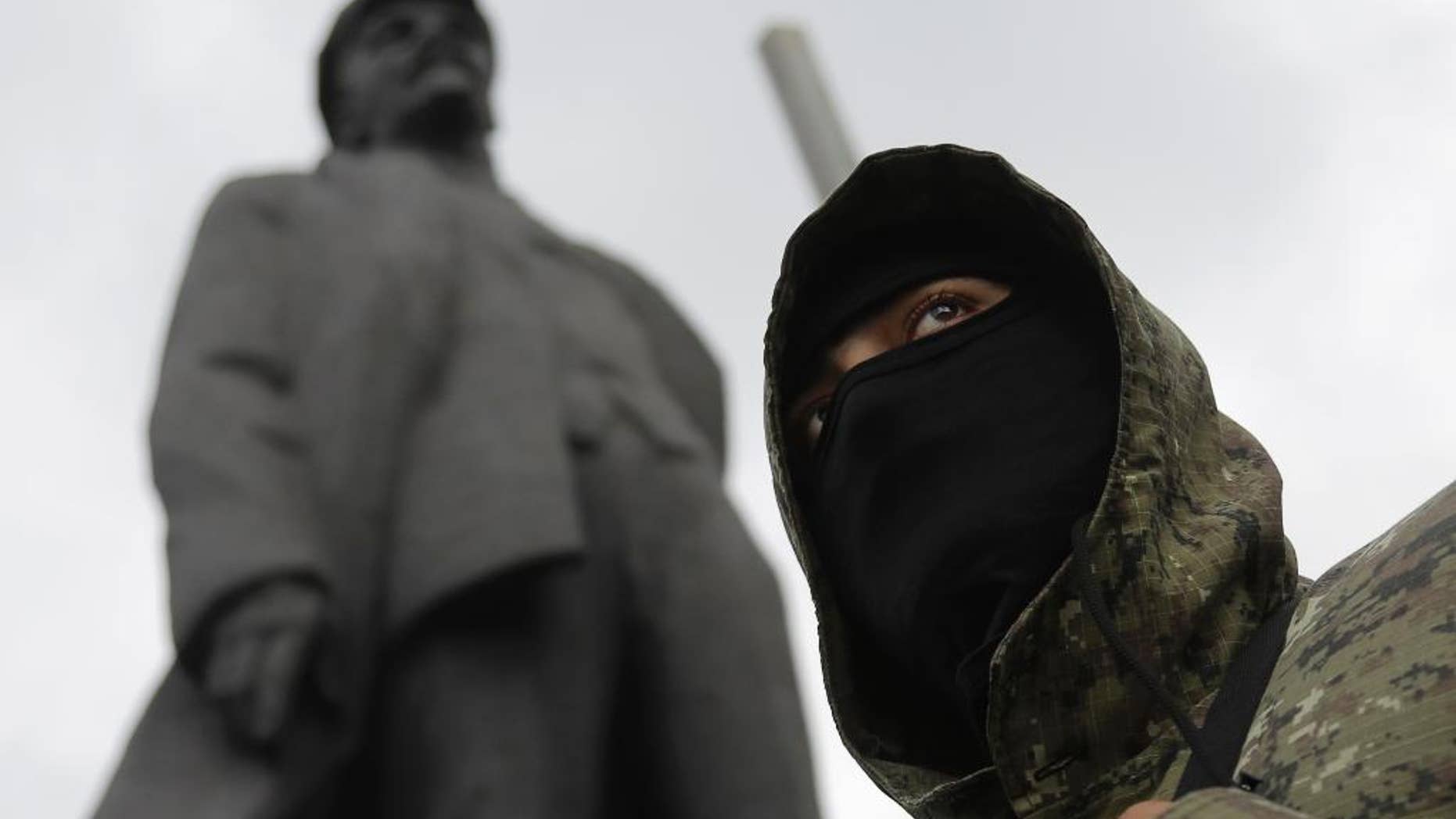 A pro-Russian fighter looks on in Donetsk, eastern Ukraine Saturday, June 21, 2014, with a statue of Soviet Union founder Vladimir Lenin on the left. Ukrainian President Petro Poroshenko ordered his forces to cease fire Friday and halt military operations for a week, the first step in a peace plan he hopes will end the fighting that has killed hundreds. The Kremlin dismissed the plan, saying it sounded like an ultimatum and lacked any firm offer to open talks with insurgents. Separatist leaders have also rejected the ceasefire and said they will not disarm. In Donetsk, a group of armed men gathered in the central square to take a military oath to the self-proclaimed Donetsk People’s Republic. (AP Photo/Dmitry Lovetsky)
