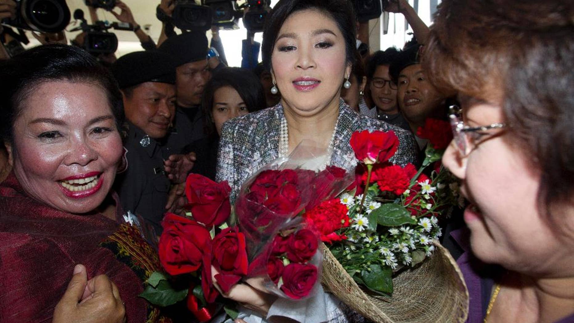 Thailand's former Prime Minister Yingluck Shinawatra, center, receives flowers from her supporters as she leaves parliament in Bangkok, Thailand, Thursday, Jan. 22, 2015. Thailand's military-appointed legislature is set to vote on impeachment against Yingluck over a government's rice subsidy scheme on Friday. AP Photo/Sakchai Lalit)