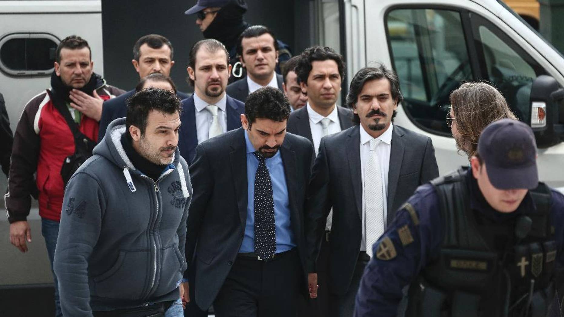 Turkish military officers, center, escorted by Greek police officers, arrive at the Supreme Court in Athens,Thursday, Jan. 26, 2017. A group of Turkish servicemen who fled to Greece in a military helicopter after last year's failed coup have appeared at Greece's Supreme Court in a closely watched extradition hearing. (AP Photo/Yorgos Karahalis)