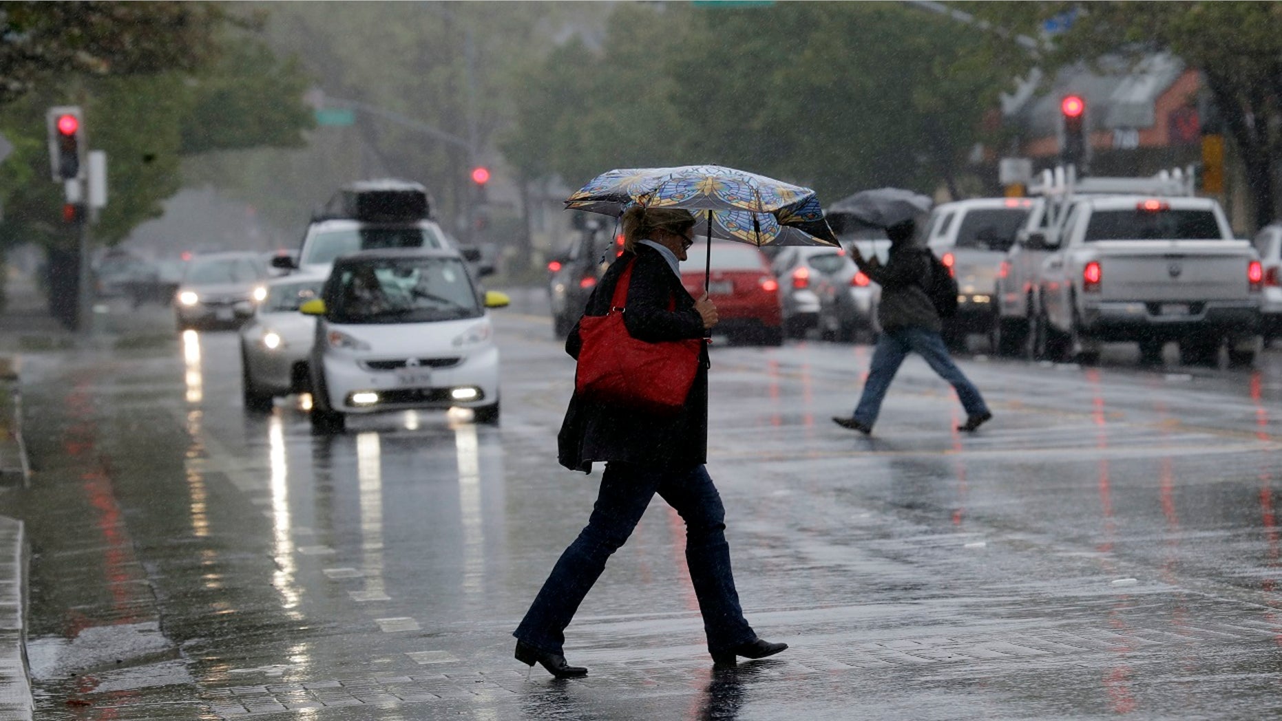Pedestrians shield themselves from the rain with umbrellas Friday, April 6, 2018, in Santa Rosa, Calif.