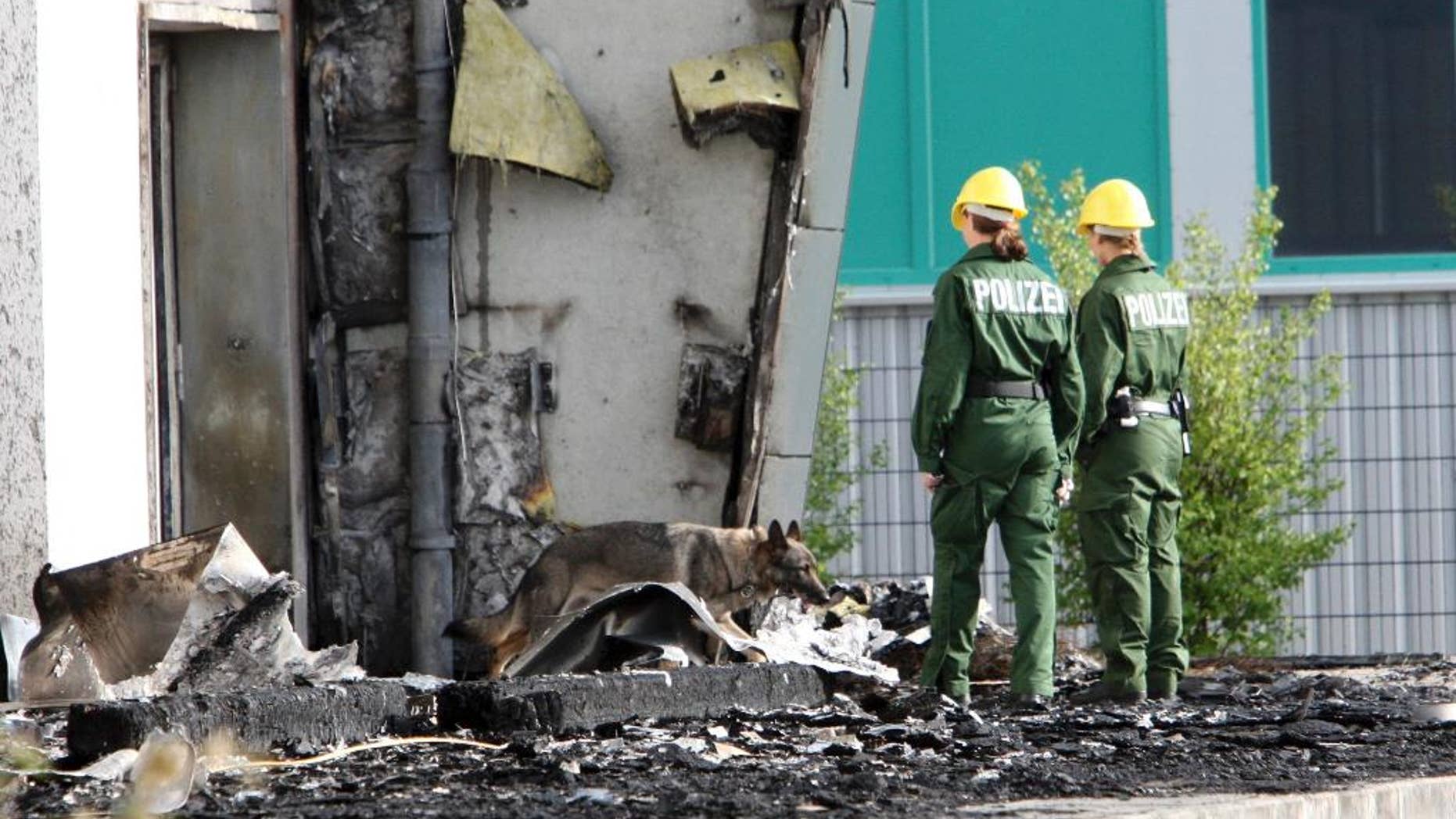 FILE - In this Aug. 26, 2015 file picture police officers and their sniffer dog examine the ruins of a burned out gym in Nauen, Germany. A German court has convicted a far-right politician for burning down the building intended as housing for refugees. The Potsdam court sentenced 29-year-old Maik Schneider, a member of the National Democratic Party, to eight years imprisonment for arson Thursday. Feb. 9, 2017. ( Nestor Bachmann/dpa via AP,file)
