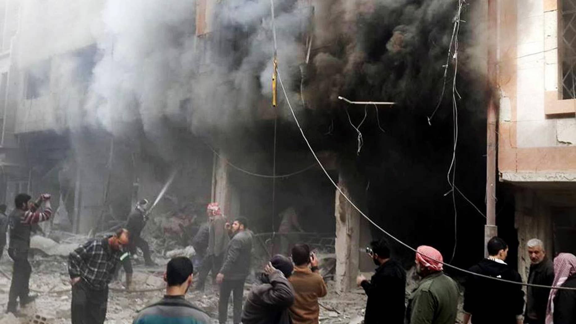 This photo released on Sunday, Dec 13, 2015 by the Douma Revolution News Network on their Facebook page, shows Syrians trying to extinguish fire that was caused by Syrian government aerial bombardment on the Damascus suburb of Douma, Syria. Syrian government helicopter gunships have struck a suburb of the capital, Damascus, a day after airstrikes on nearby areas killed more than 40 people, opposition activists said. (Douma Revolution via AP)