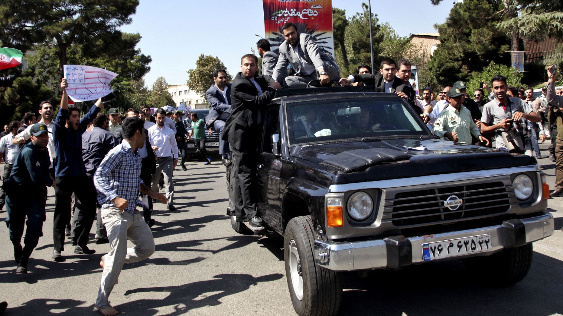 A protester, left, approaches President Hassan Rouhani's car leaving Mehrabad airport after his arrival from the U.S. in Tehran, Iran, Saturday, Sept. 28, 2013. Iranians from across the political spectrum hailed Saturday the historic phone conversation between President Barack Obama and his Iranian counterpart Rouhani, reflecting wide support for an initiative that has the backing of both reformists and the country's conservative clerical leadership. Despite the broad-based praise, the hard-liners opposed to any improved contact with Washington made their objections clear at Rouhani's arrival in Tehran. Several dozen protesters chanted "Death to America" and tried to block Rouhani's motorcade.(AP Photo/Ebrahim Noroozi)