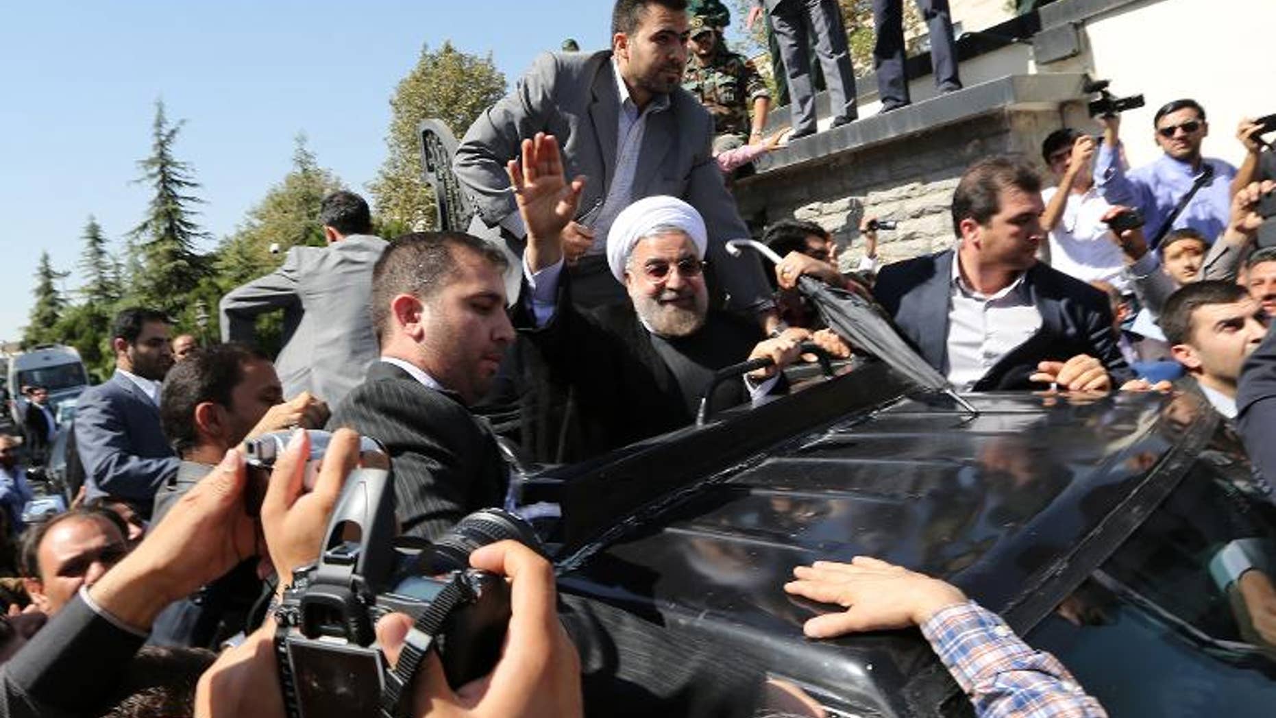 Iranian president Hassan Rouhani waves to supporters as his motorcade draws out of Tehran's Mehrabad Airport upon his arrival from New York, on September 28, 2013