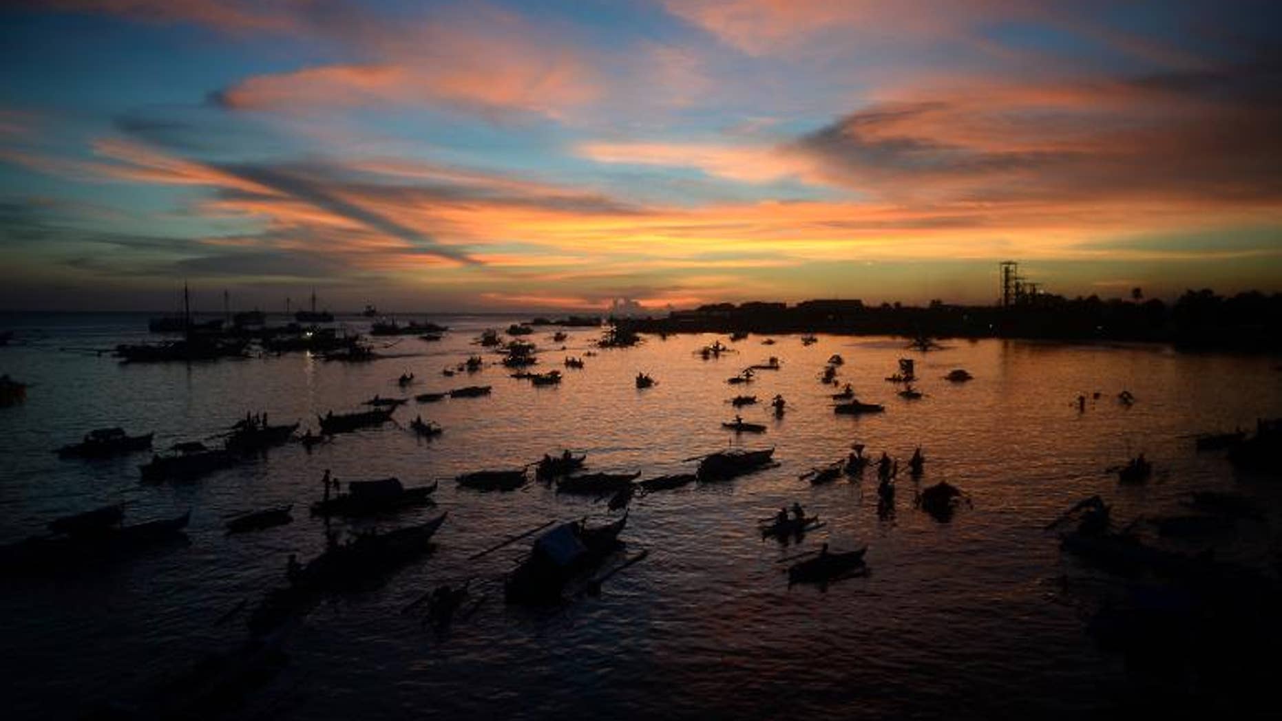 Evacuees affected by the stand-off between Philippine government forces and Muslim rebels sit anchored in their wooden boats used also as temporary living quarters at sunset near the sea wall in Zamboanga on September 14, 2013.
