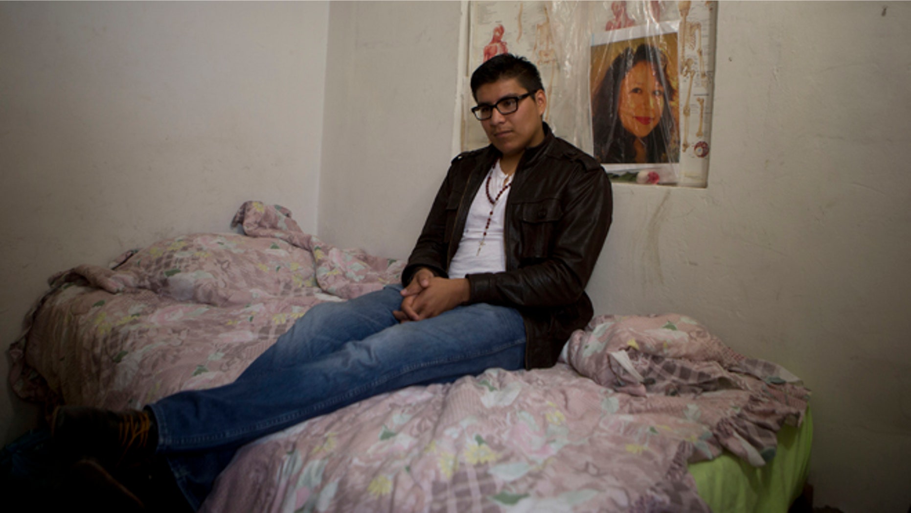 In this Friday, Oct. 3, 2014 photo, Dario Guerrero sits for a portrait in his bedroom with a picture of his late mother, at his grandparents' home on the outskirts of Mexico City. Guerrero, a Harvard University junior, accompanied his dying mother to Mexico without government permission, and is now unable to return to the United States. (AP Photo/Dario Lopez-Mills)