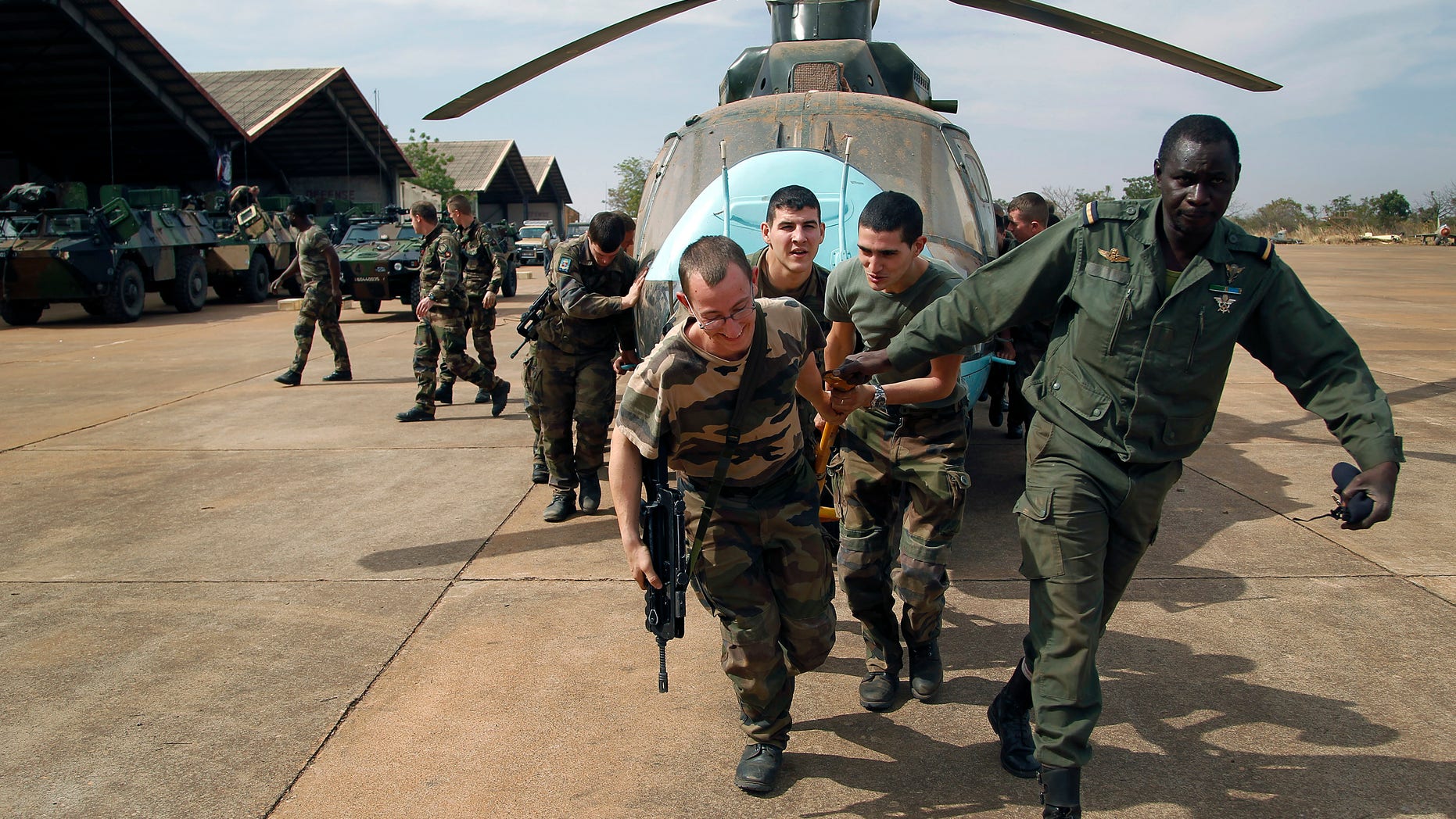 Malian soldiers helped by French troops, move a broken helicopter out a hangar to make room for more incoming troops at Bamako's airport Tuesday Jan. 15. 2013. French forces led an all-night aerial bombing campaign Tuesday to wrest control of a small Malian town from armed Islamist extremists who seized the area, including its strategic military camp. A a convoy of 40 to 50 trucks carrying French troops crossed into Mali from Ivory Coast as France prepares for a possible land assault. Several thousand soldiers from the nations neighboring Mali are also expected to begin arriving in coming days. (AP Photo/Jerome Delay)