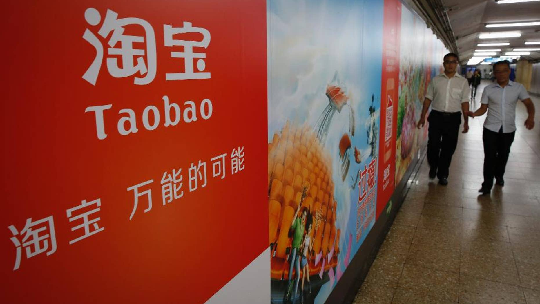 FILE - In this Sept. 18, 2014 file photo, people walk past an advertising billboard showing the mobile app of Alibaba’s Taobao consumer-to-consumer site at a subway station in Beijing. Alibaba Group Holding Ltd. reports quarterly financial results before the market opens on Wednesday, Aug. 12, 2015. (AP Photo/Vincent Thian, File)