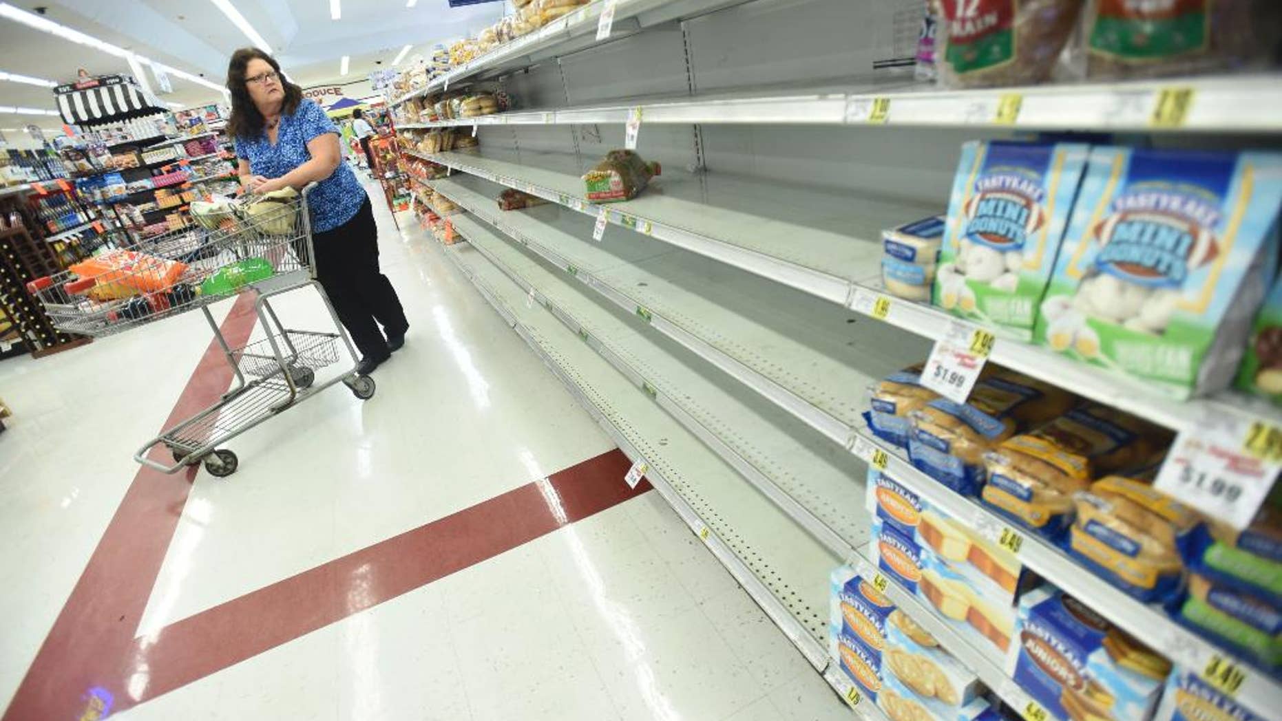 Mary Stanley looks at the empty shelves on a bread isle at the Piggly Wiggly grocery store in Leland, N.C., on Wednesday, Oct. 5, 2016. Forecasters said Hurricane Matthew could hit Florida — or come dangerously close — late Thursday or early Friday and then scrape the East Coast all the way up to the Carolinas over the weekend. (Ken Blevins/The Star-News via AP) /The Star-News via AP)