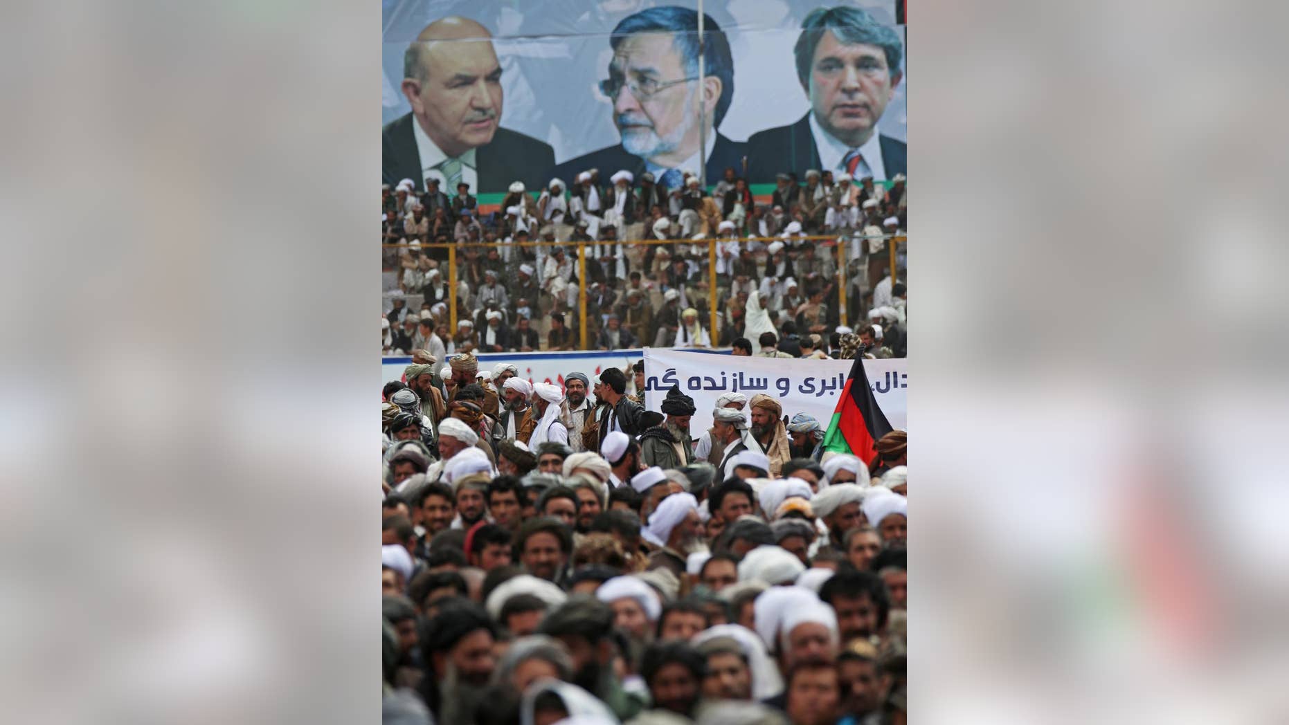 Supporters of Afghanistan's presidential candidate and former foreign minister Zalmai Rassoul, listen to his speech during a campaign rally in Herat, Afghanistan, Sunday, March 30, 2014. The poster shows a photo of Zalmai Rassoul, center, and two brothers of Afghan president Hamid Karzai's photos. Eight Afghan presidential candidates are campaigning for the third presidential election. Elections will take place on April 5, 2014. (AP Photo/Massoud Hossaini)