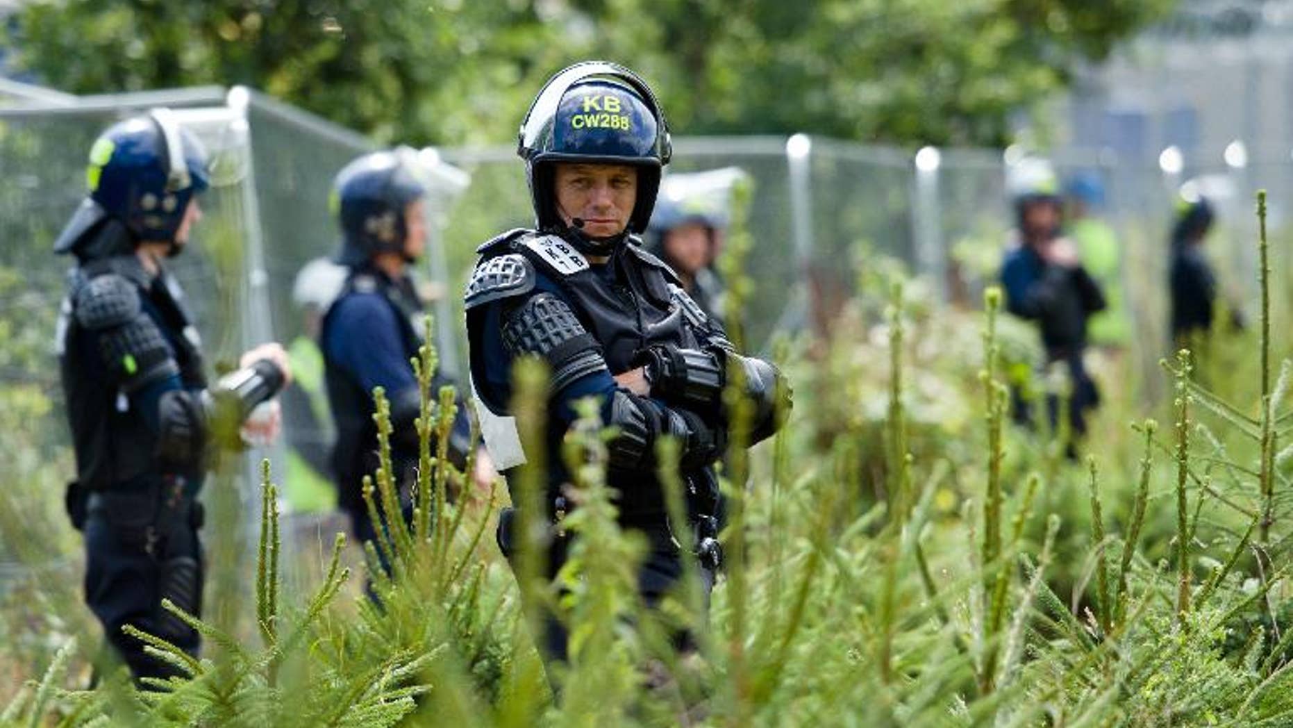Police officers in body armour line the perimeter fence of the test drill site operated by British energy firm Cuadrilla Resources in Balcombe, southern England, on August 20, 2013, as anti-fracking activists hold a protest camp nearby.