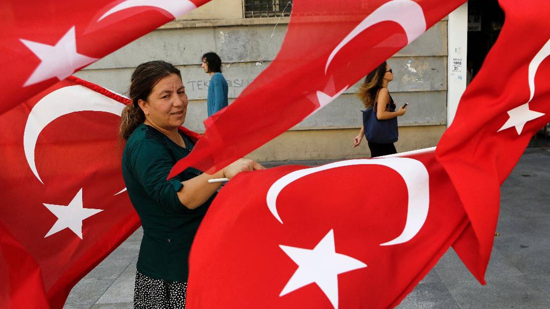 A woman sales Turkish flags in Istanbul, on Saturday, July 30, 2016. Turkey has demanded the United States extradite Fethullah Gulen, a cleric living in self-imposed exile in Pennsylvania whom it accuses of being behind the violent July 15 coup attempt that left more than 200 people dead. (AP Photo/Petros Karadjias)