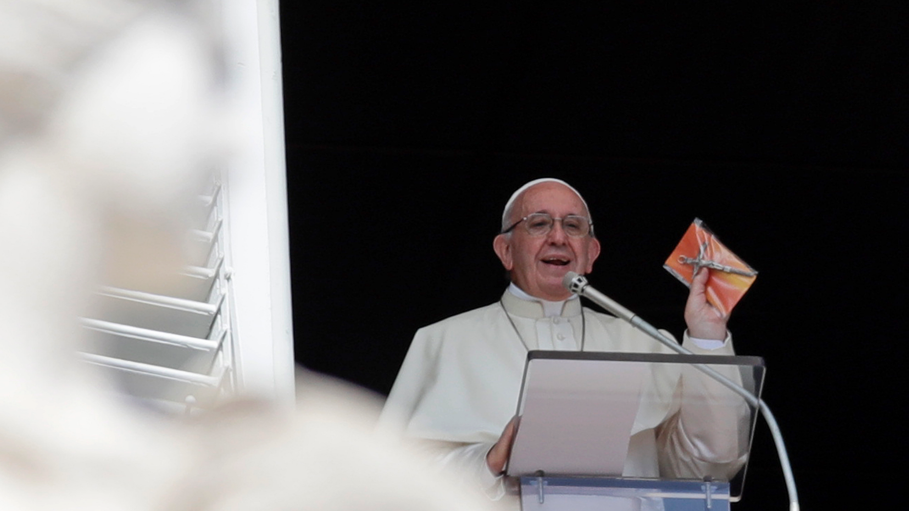 Pope Francis shows a crucifix during the Angelus noon prayer he delivers from the window of his studio overlooking St. Peter's Square at the Vatican, Sunday, Sept. 16, 2018. Tens of thousands of faithful have been treated to gifts from the pontiff, tiny crucifixes, distributed by nuns, refugees and some of Rome's homeless and poor after the pope’s traditional Sunday appearance to pilgrims and tourists in the square. (AP Photo/Alessandra Tarantino)