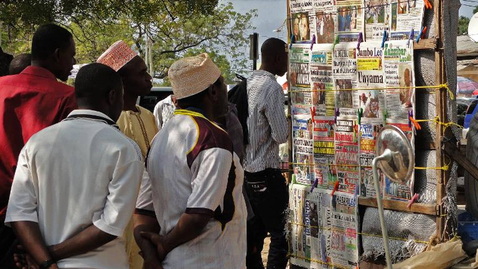 Locals look at newspaper headlines in Stone Town on the Indian Ocean island of Zanzibar on August 9, 2013