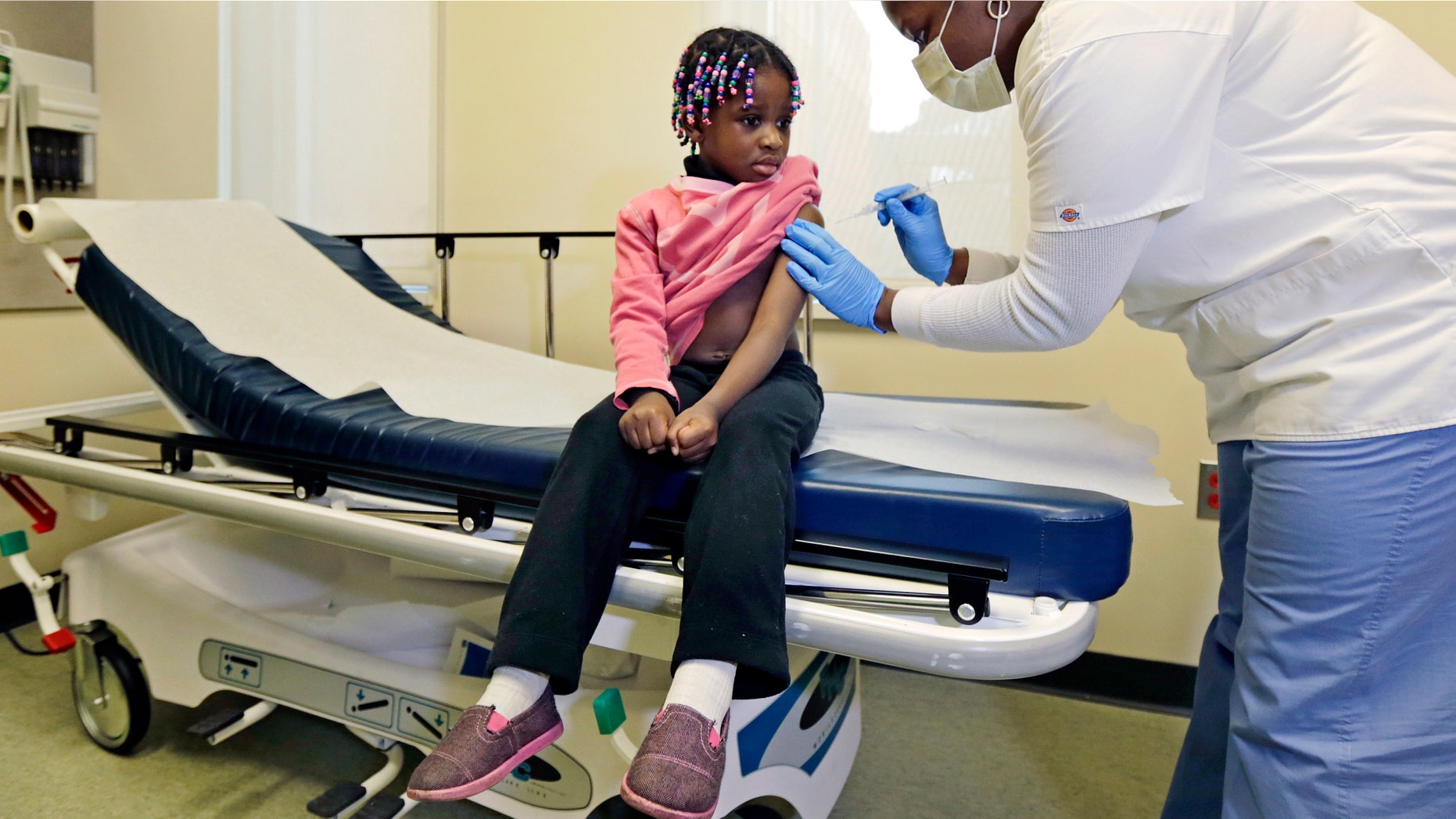 Four-year-old Gabriella Diaz sits as registered nurse Charlene Luxcin, right, administers a flu shot at the Whittier Street Health Center in Boston, Mass. (AP Photo/Charles Krupa)