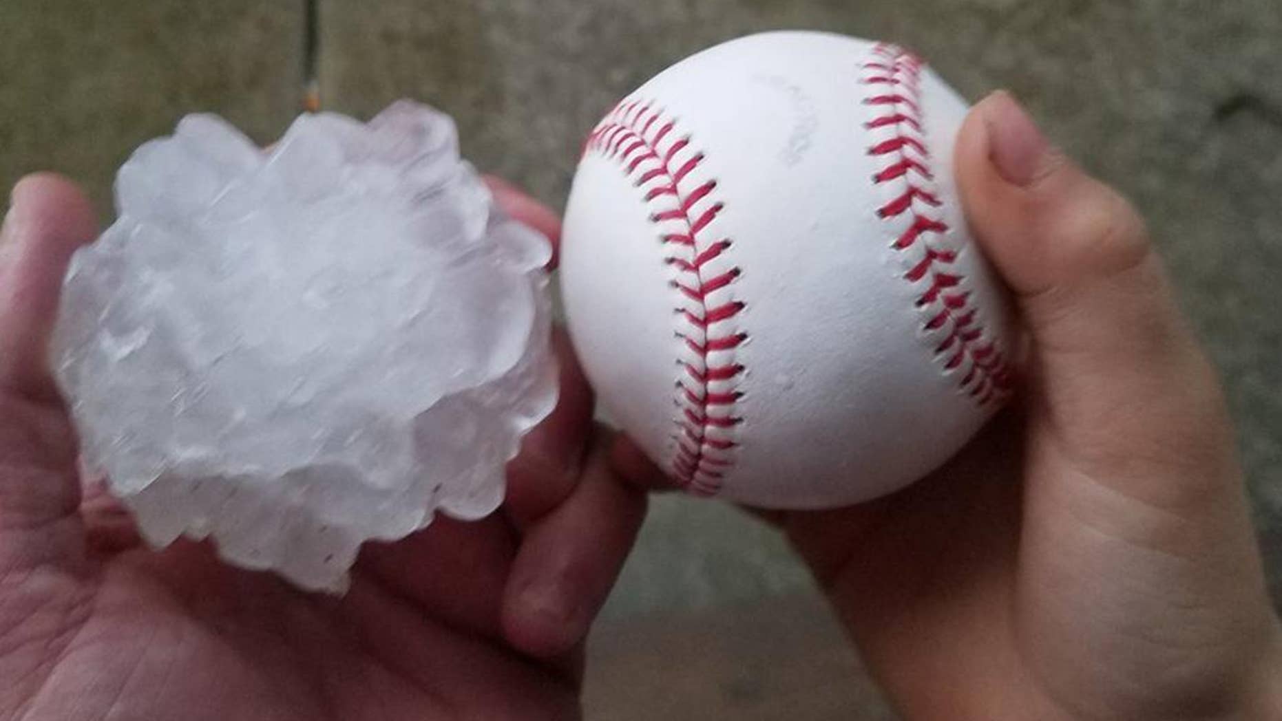 This photo provided by Tim Creedon shows his baseball and a hailstone that fell in the backyard of Creedon's home in Ottawa, Ill., Tuesday, Feb. 28, 2017. Illinois Gov. Bruce Rauner has activated the state's emergency operations center as local officials reported damage from tornados spawned by a late-winter storm system. (Tim Creedon via AP)