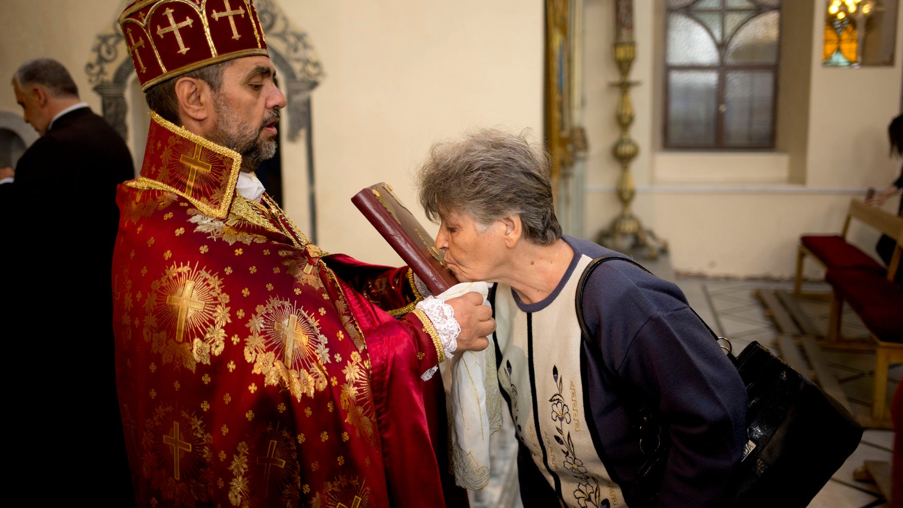 FILE -- Oct. 27, 2013: a woman kisses the Bible during a service in an Armenian Orthodox church in Damascus, Syria. (The Associated Press)