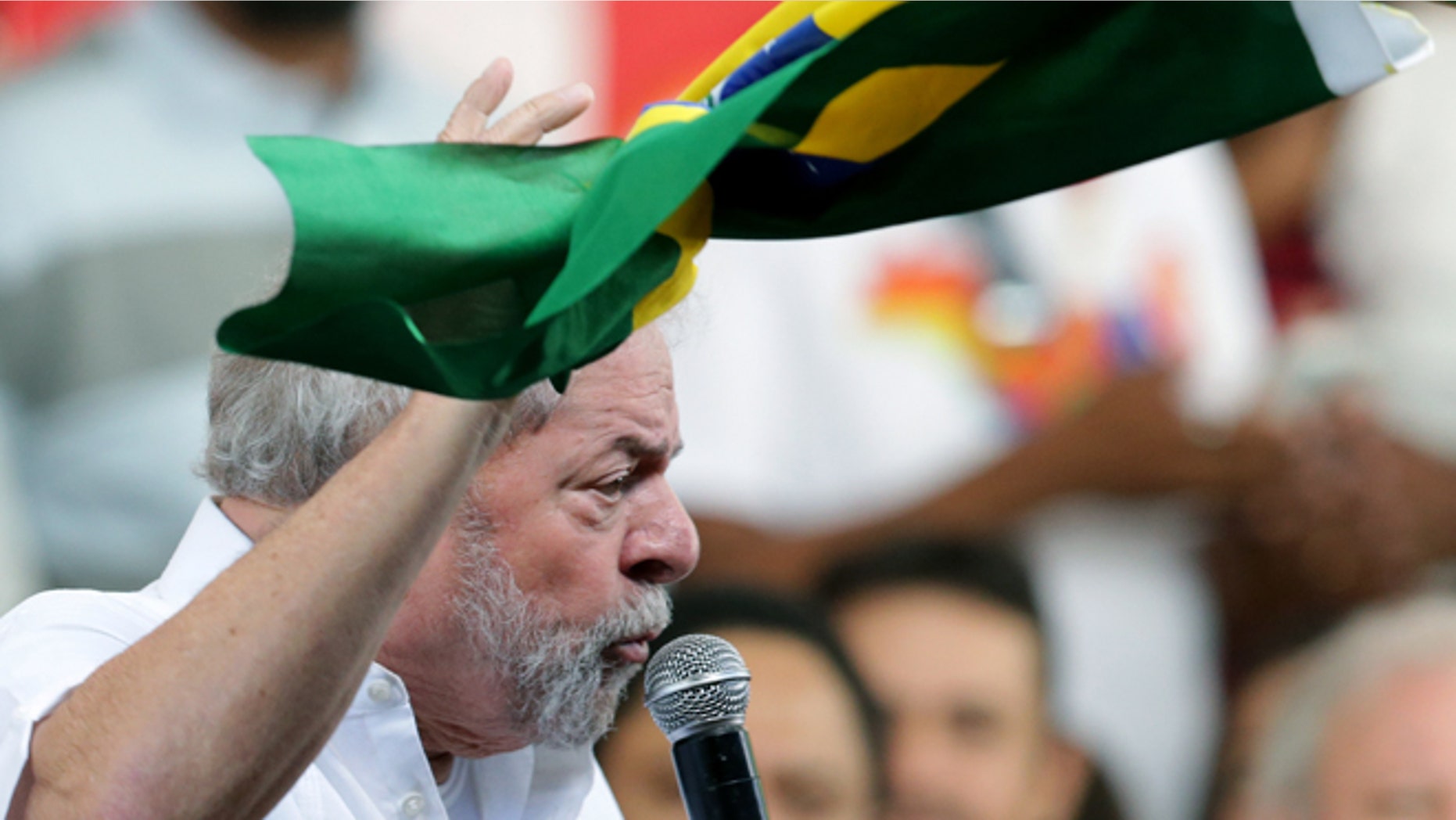 Brazil's former President Luiz Inacio Lula da Silva, holds a Brazilian flag, while speaking during a rally of Social Movements for Democracy, in a camp set up by supporters of President Dilma Rousseff in Brasilia, Brazil, Saturday, April 16, 2016. The lower chamber of Brazil's Congress on Friday began a debate on whether to impeach Rousseff, a question that underscores deep polarization in Latin America's largest country and most powerful economy. The crucial vote is slated for Sunday. (AP Photo/Eraldo Peres)