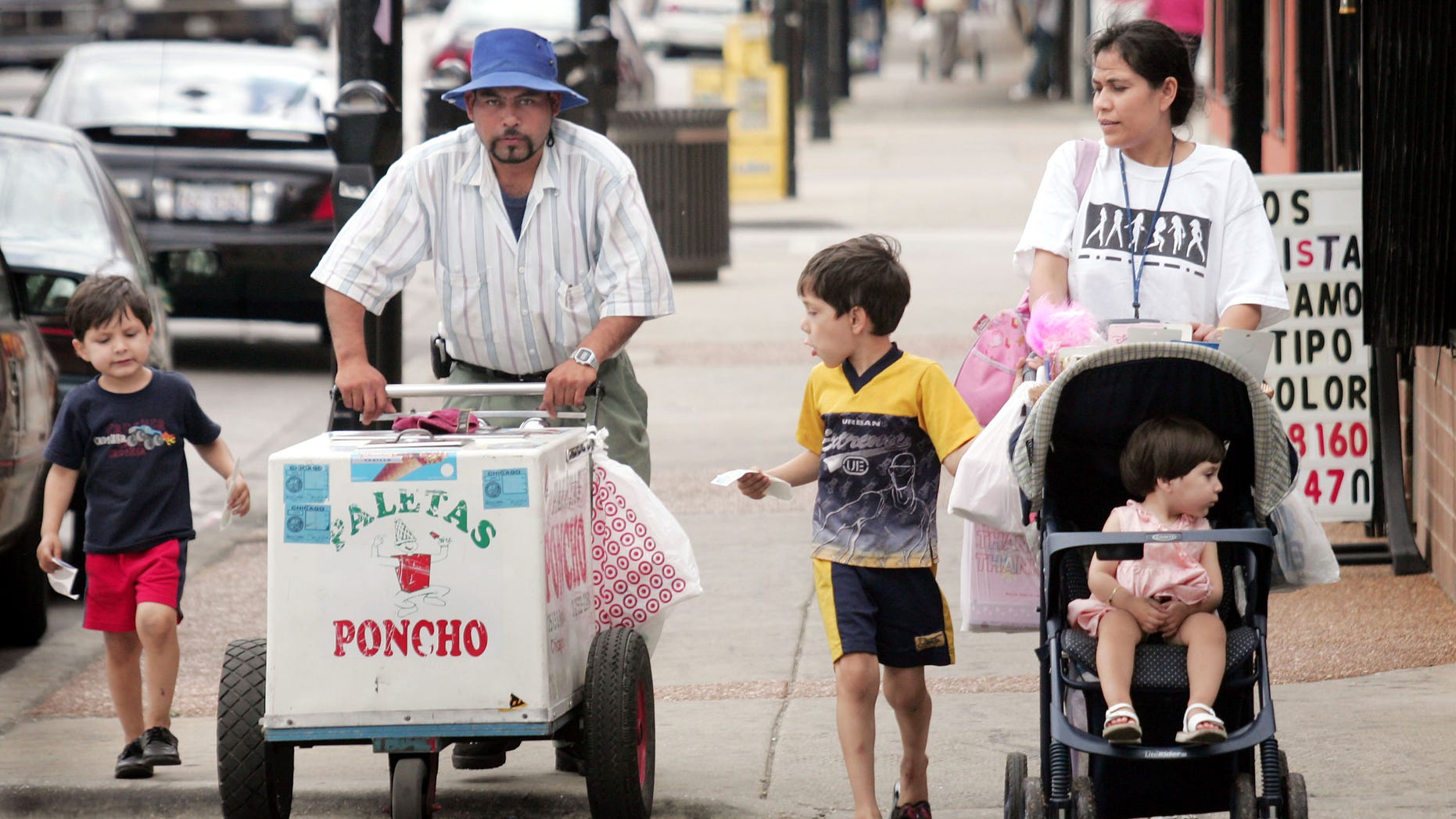 CHICAGO - JUNE 14: Residents walk past a paleta vendor along 26th Street in the predominantly Mexican Little Village neighborhood June 14, 2005 in Chicago, Illinois. According to the U.S. census Hispanics accounted for approximately half of the national population growth between July 1, 2003 and July 1, 2004 now accounting for one-seventh of the population. (Photo by Scott Olson/Getty Images)