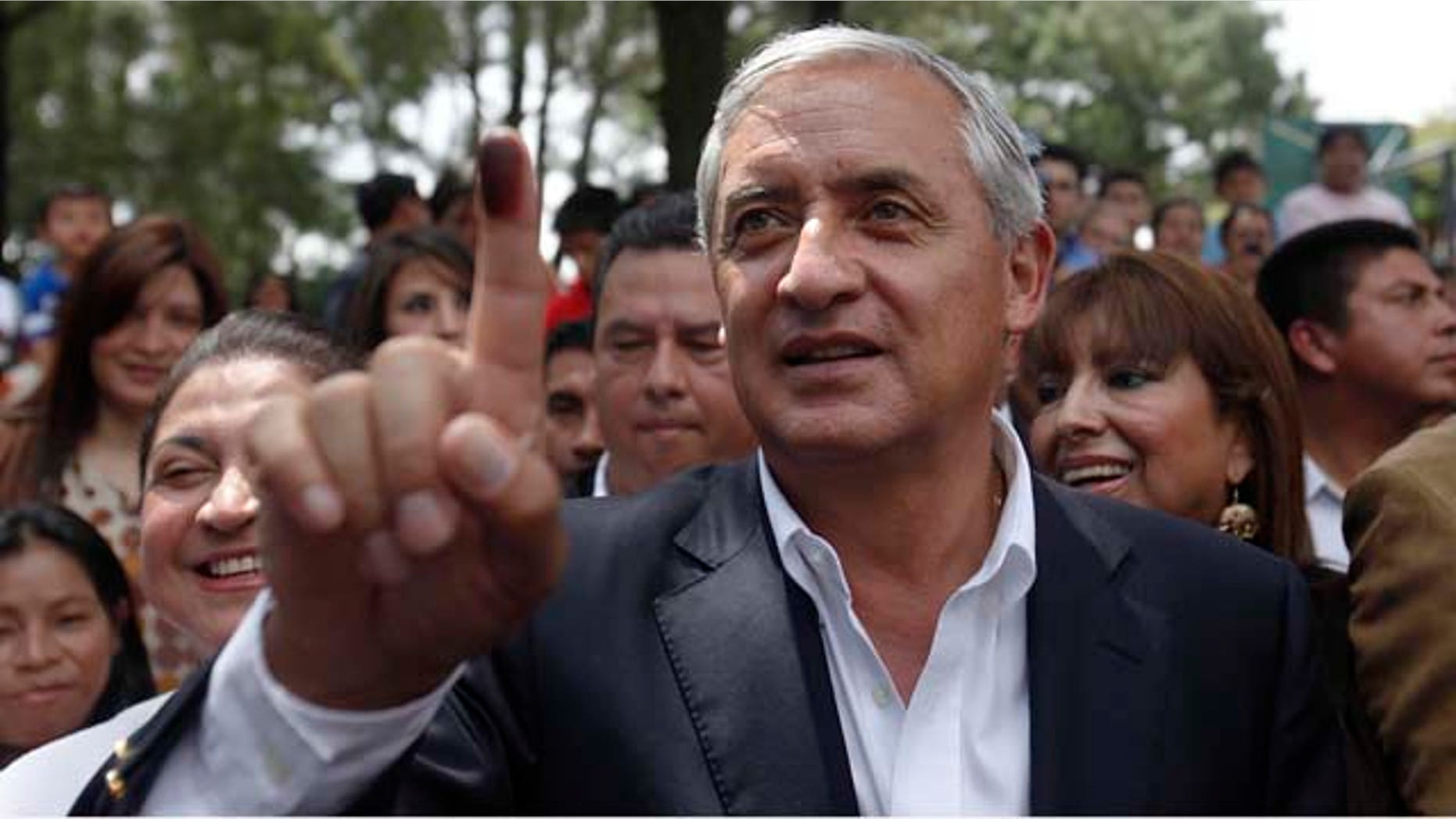 Guatemala's presidential candidate of the Patriotic Party Otto Perez Molina, shows his ink-stained thumb after casting his vote at a polling during the country's presidential elections in Guatemala City, Sunday, Sept. 11, 2011. (AP Photo/Moises Castillo)