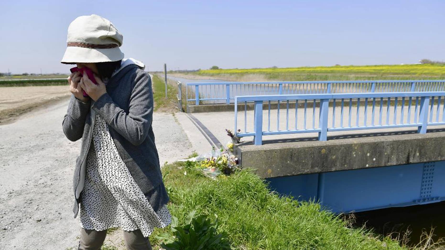 A woman sobs after offering flowers where a 9-year-old Vietnamese girl was found dead in Abiko, near Tokyo, Friday, April 14, 2017. Police have arrested a Japanese man in connection with the girl's death, weeks after her naked body was found near a trench. Chiba prefectural police said Friday they arrested 46-year-old real estate salesman Yasumasa Shibuya on suspicion he abandoned the girl's body. Japanese media say Shibuya headed a parents' association at the school the girl attended. (Ren Onuma/Kyodo News via AP)