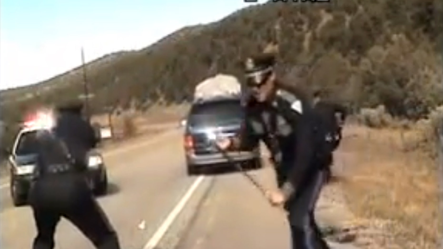 Three New Mexico State Police officers react as a minivan driven by motorist Oriana Farrell pulls away from a chaotic traffic stop that included one officer bashing the van’s window with his night stick and another, Elias Montoya, at left, firing three shots as the van drives off, in this video made Oct. 28, from the dashboard camera of the police cruiser. Montoya, the officer who fired at the van full of children, has been suspended. (AP Photo/New Mexico State Police)