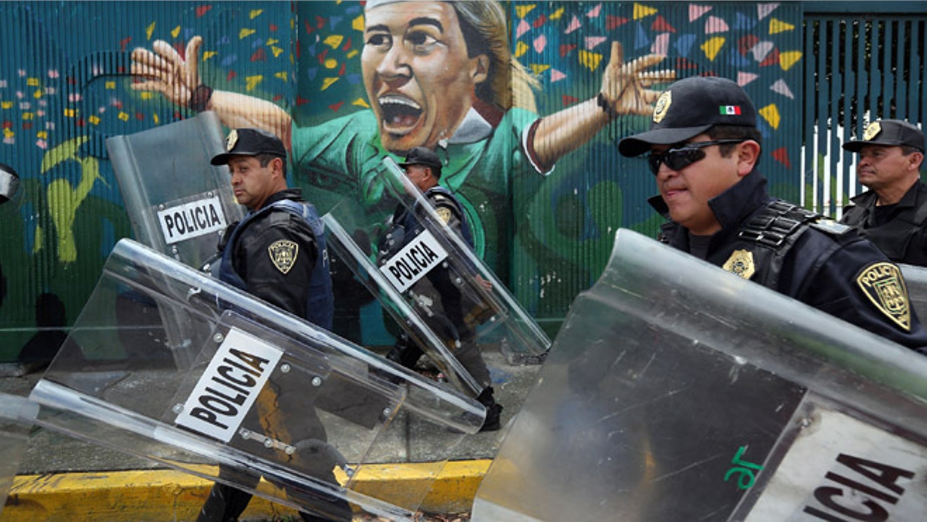 MEXICO CITY, MEXICO - JUNE 24: Police walk past a mural of Mexican soccer legend Luis Hernandez at the Azteca soccer stadium following the final campaign rally of Enrique Pena Nieto, presidential candidate for the Institutional Revolutionary Party (PRI), on June 24, 2012 in Mexico City, Mexico. Pena Nieto leads the polls going into the July 1 presidential election. If he wins, the PRI will return to power twelve years after losing the presidency to the ruling National Action Party (PAN), in 2000. (Photo by John Moore/Getty Images)