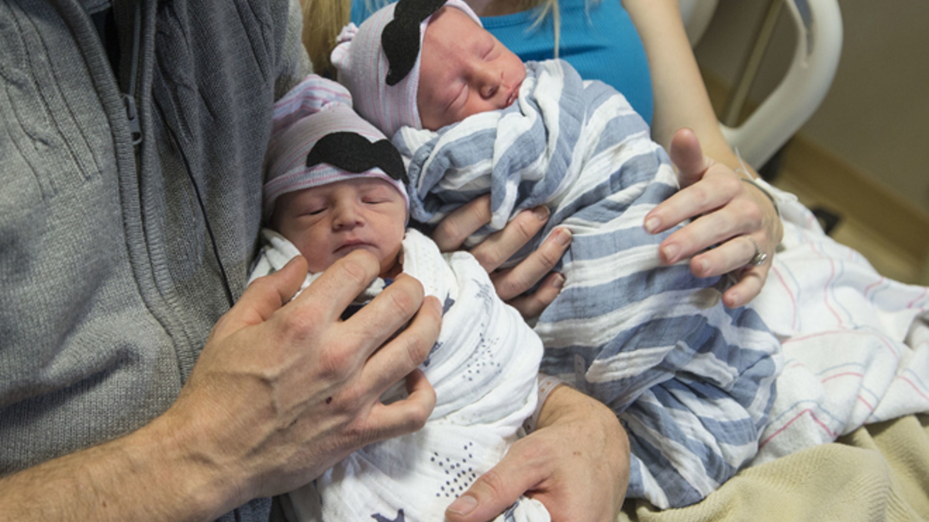 In a Jan. 1, 2017 photo, Brandon Shay, and his wife Holly of Glendale, Ariz., hold their new born twins at at Banner Hospital in Glendale. The couple welcomed their first son, Sawyer, right, into the world at 11:51 p.m. Saturday. Their second son, Everett, arrived one minute after midnight on Sunday. (Nick Oza/The Arizona Republic via AP)
