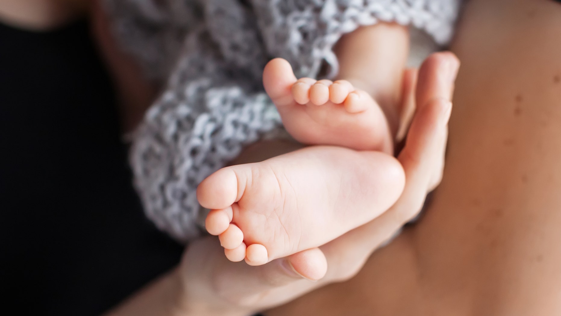 Baby feet in mother hands. Tiny Newborn Baby's feet on female Shaped hands closeup. Mom and her Child. Happy Family concept. Beautiful conceptual image of Maternity