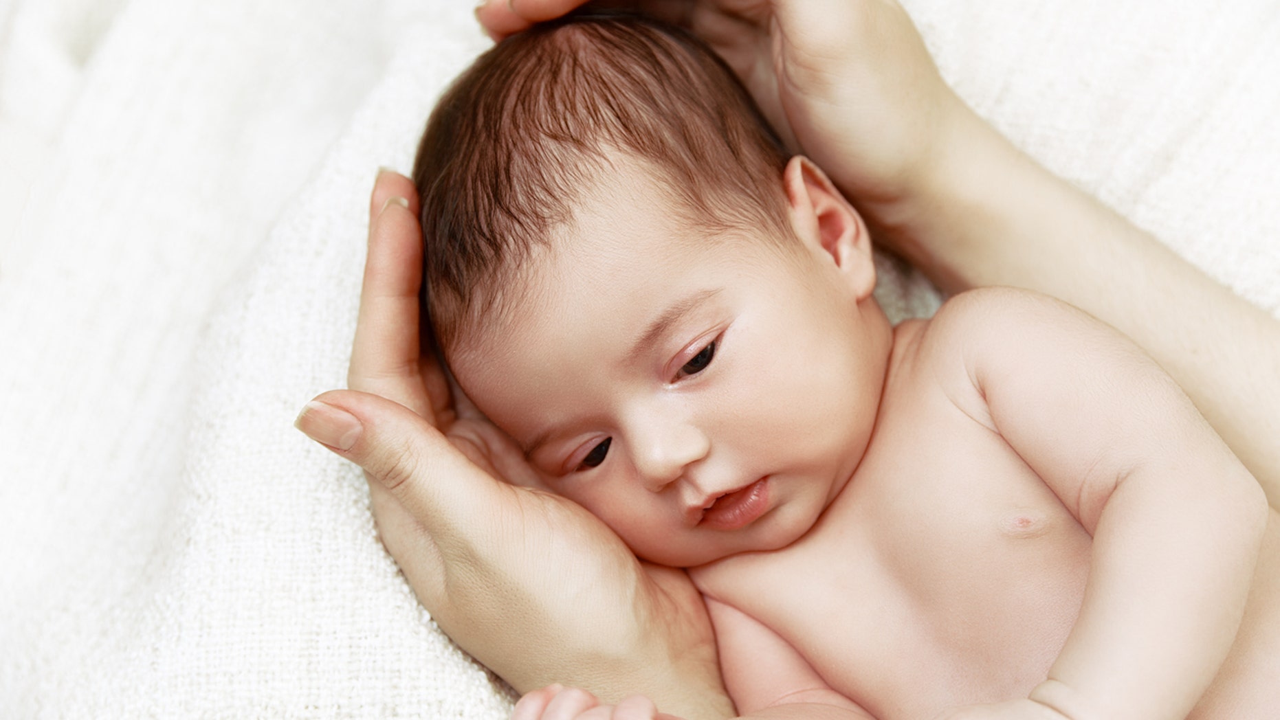 Cute newborn baby lying in mother's hands