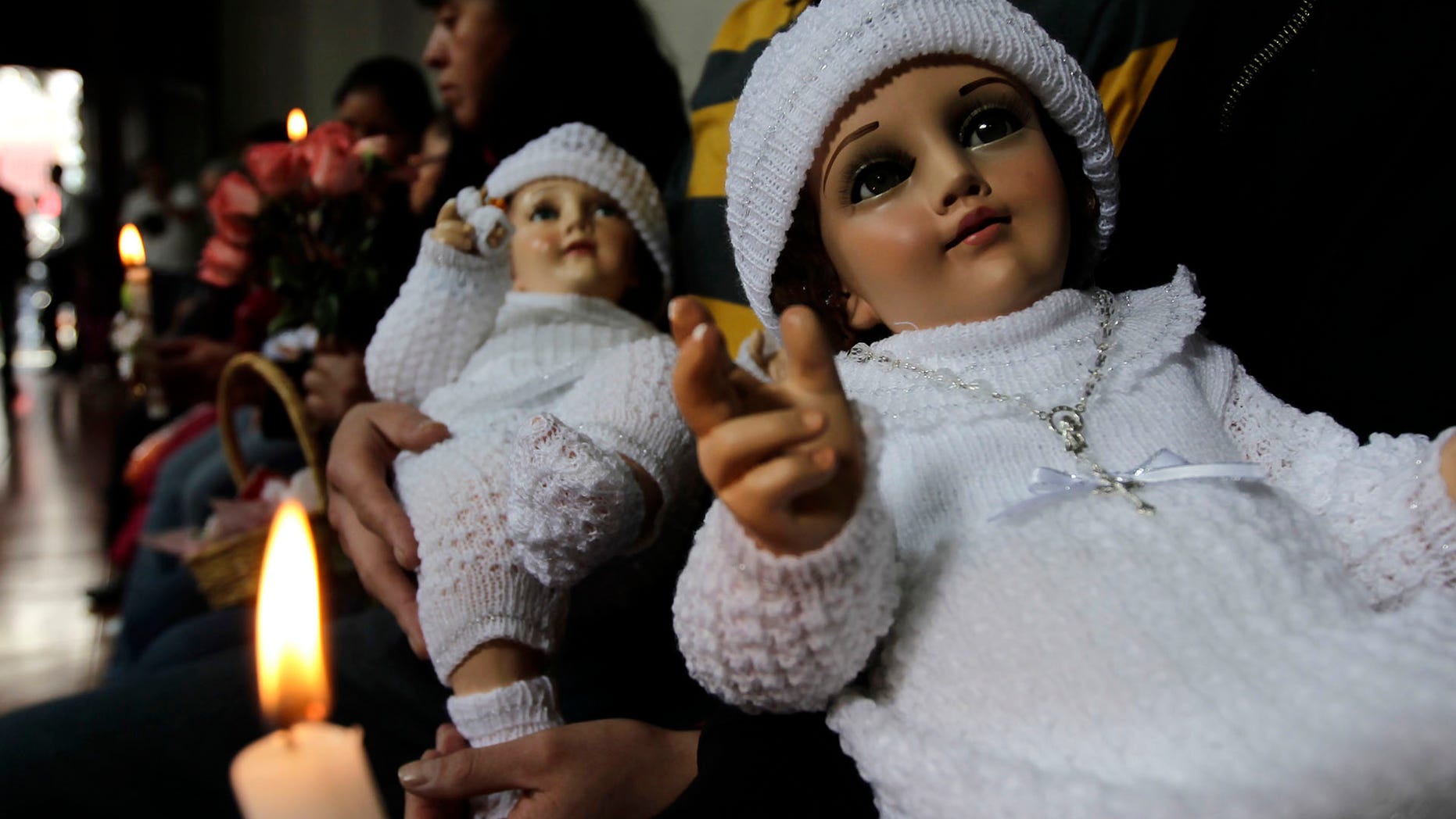 People hold dressed-up dolls representing baby Jesus during a mass in La Candelaria church in Mexico City.