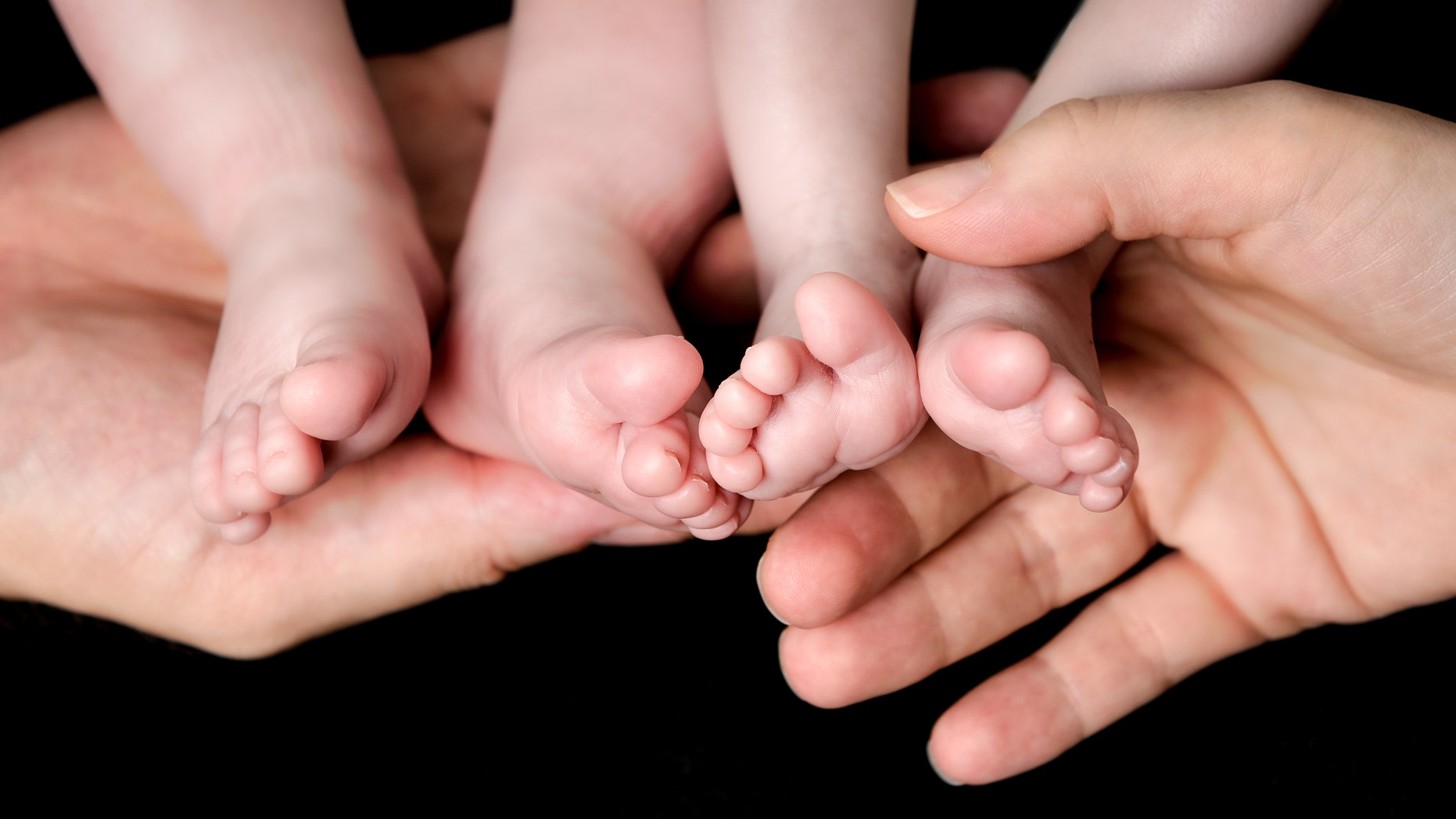 Little Baby Twins Feet in parents hands. Parenthood, family, twins, children and love concept.